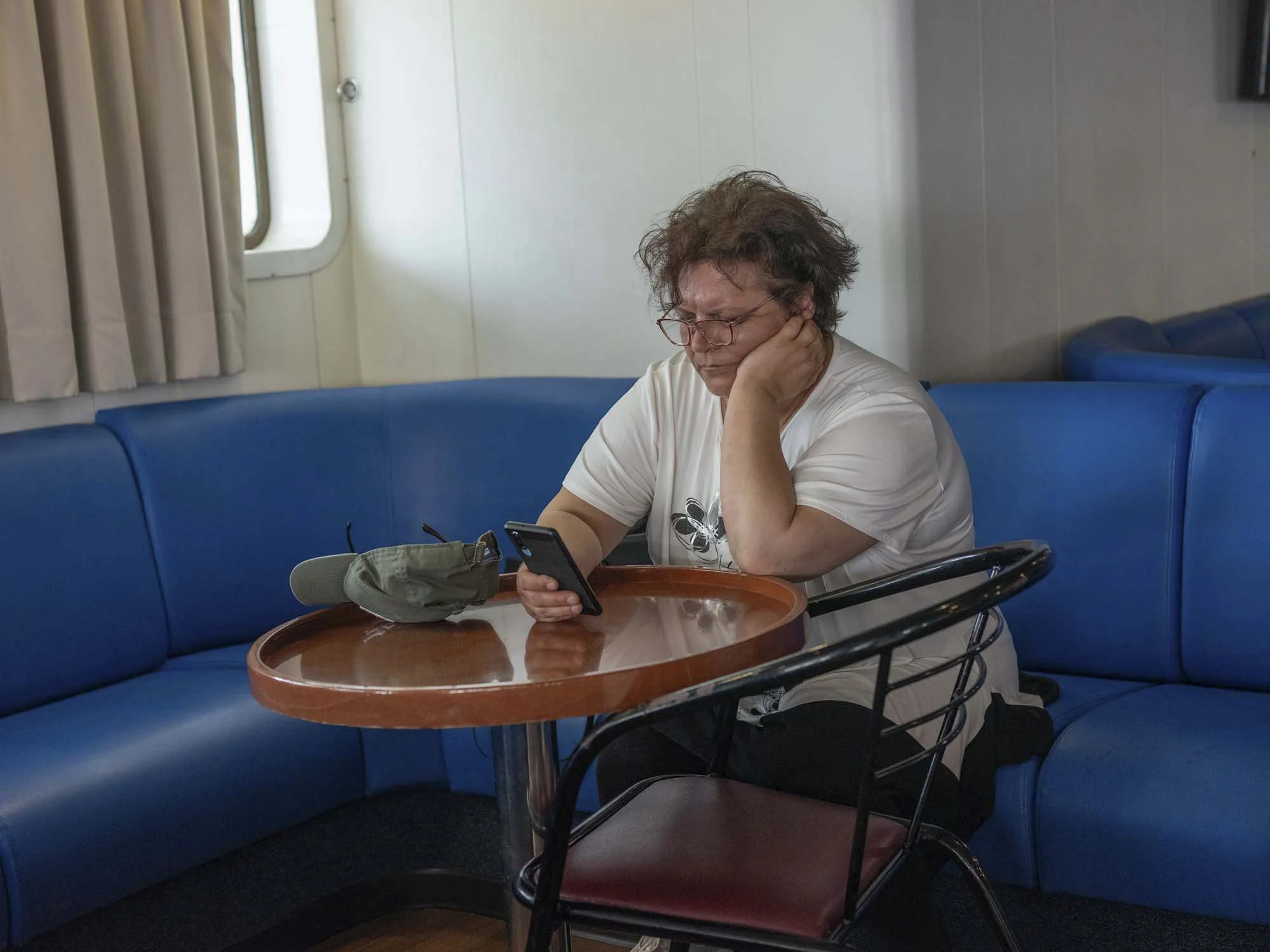Commuters on the early morning ferry from Split to Brač, Croatia, resting and using smartphones on the deck, documentary photography by Roman Bezjak