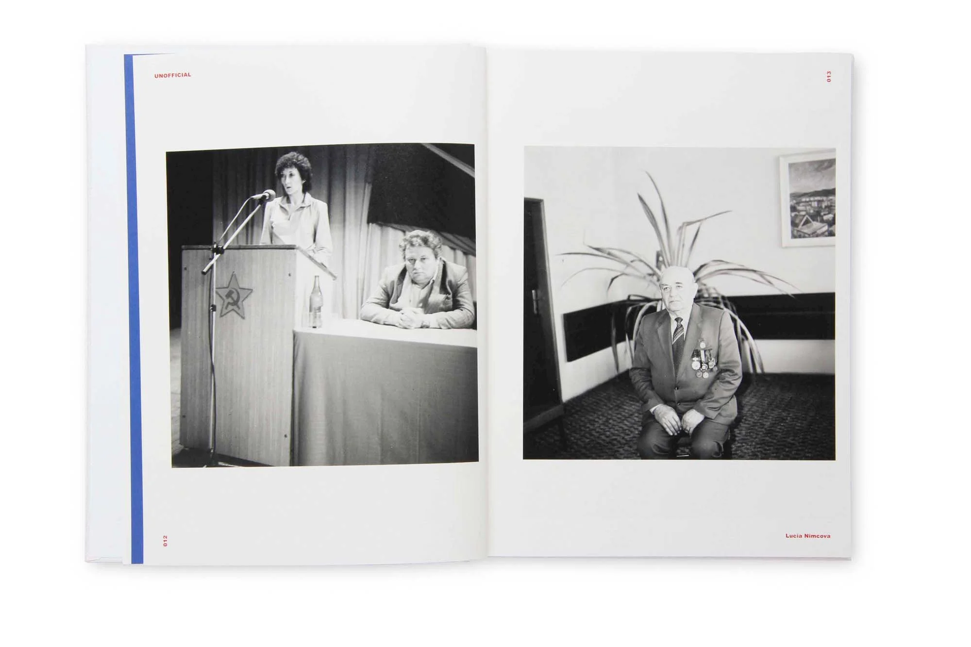 Zwei schwarze und weiße Fotografien in einem offenen Buch. Die linke Fotografie zeigt eine Frau, die an einem Rednerpult spricht, während ein Mann daneben sitzt. Die rechte Fotografie zeigt einen alten Mann in einem Anzug mit Medaillen, der vor einem
