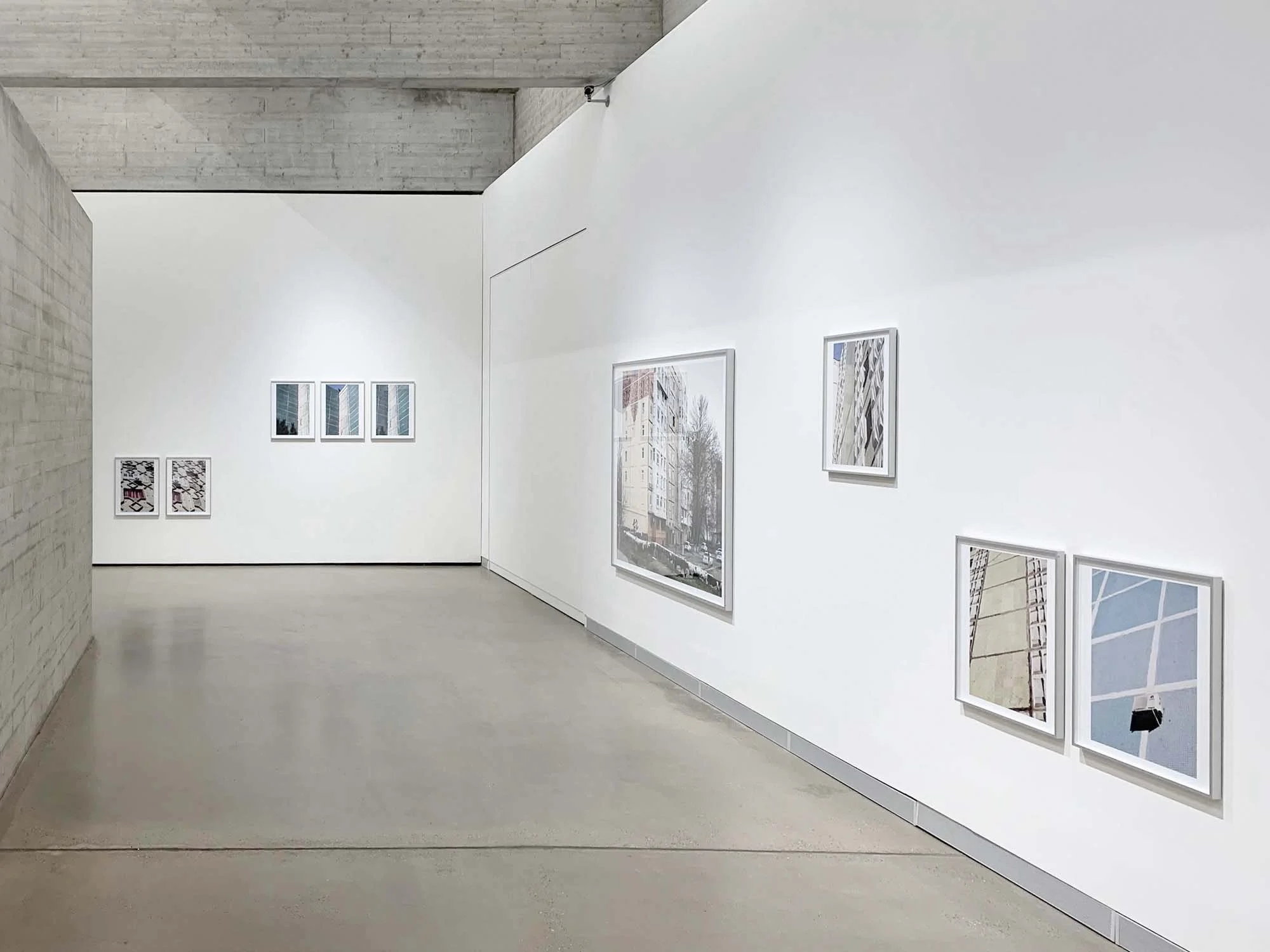 Bilder in einem Kunstgalerie mit Stadtbildern an einer weißen Wand.