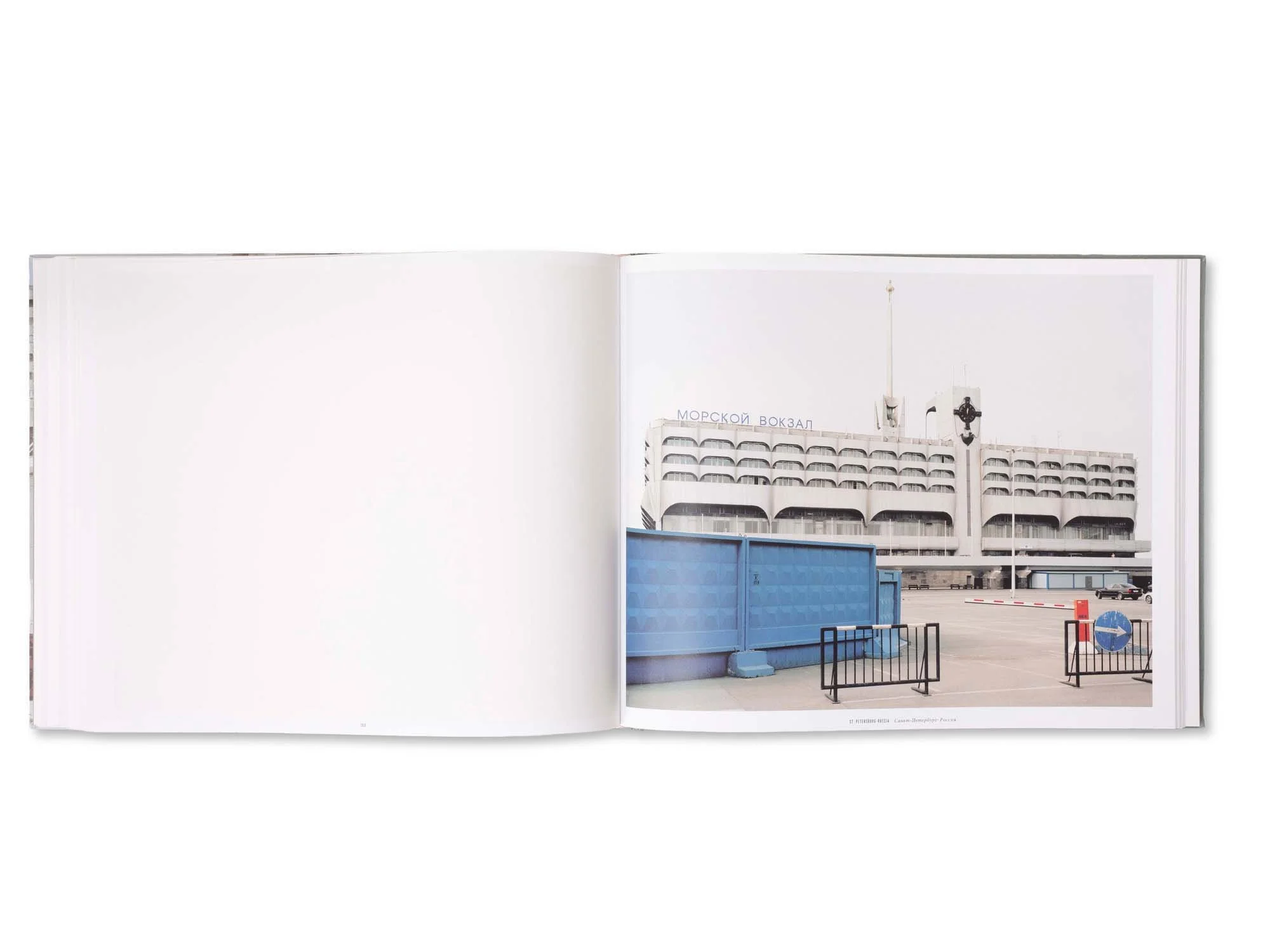 Fotobuch mit einem Bild des Flughafens Morceau Vokzal, mit Blauer Frachtcontainer, Metallstab und schwarzem Geländer auf dem Rollfeld.
