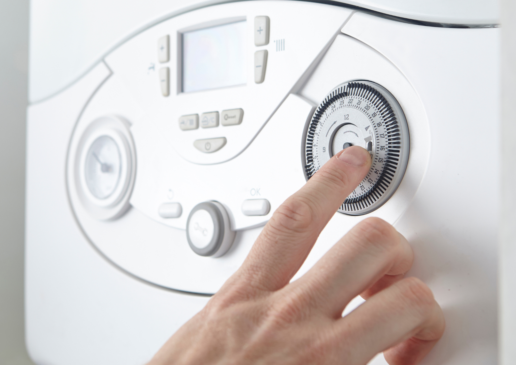 Close-up of a person's hand turning a dial on a white washing machine.