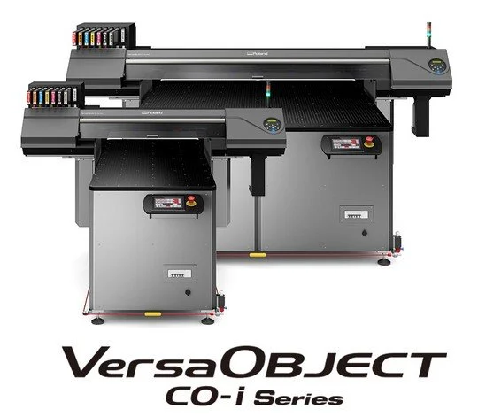 Large digital flatbed printer with two workstations and ink cartridges on top, branded VersaOBJECT CO-i Series.