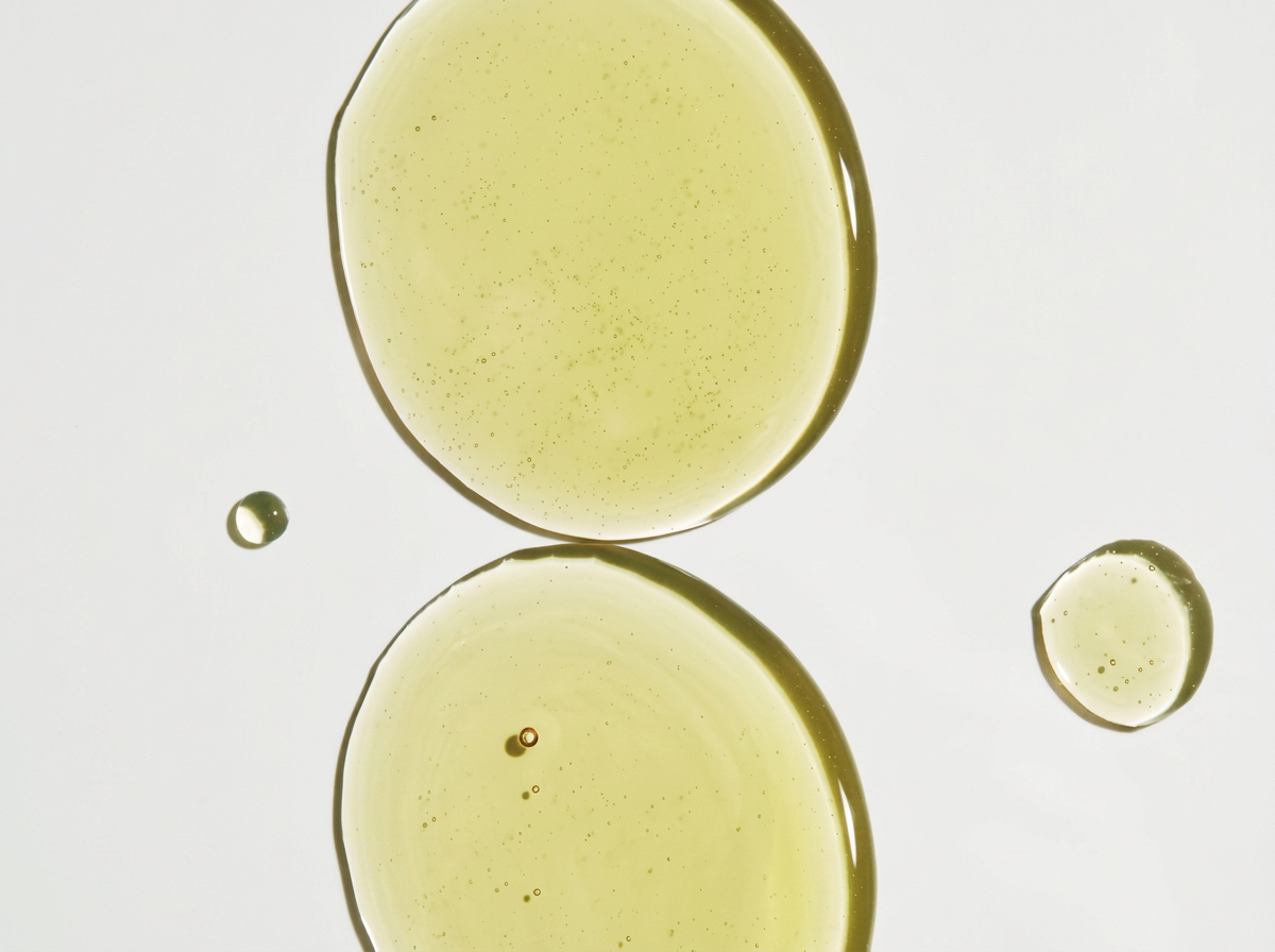 Close-up of four droplets of The Bounce breast oil on a white background