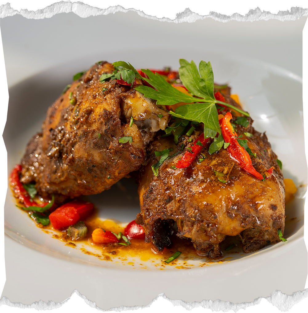 Two braised beef shanks garnished with chopped herbs and sliced red peppers on a white plate.