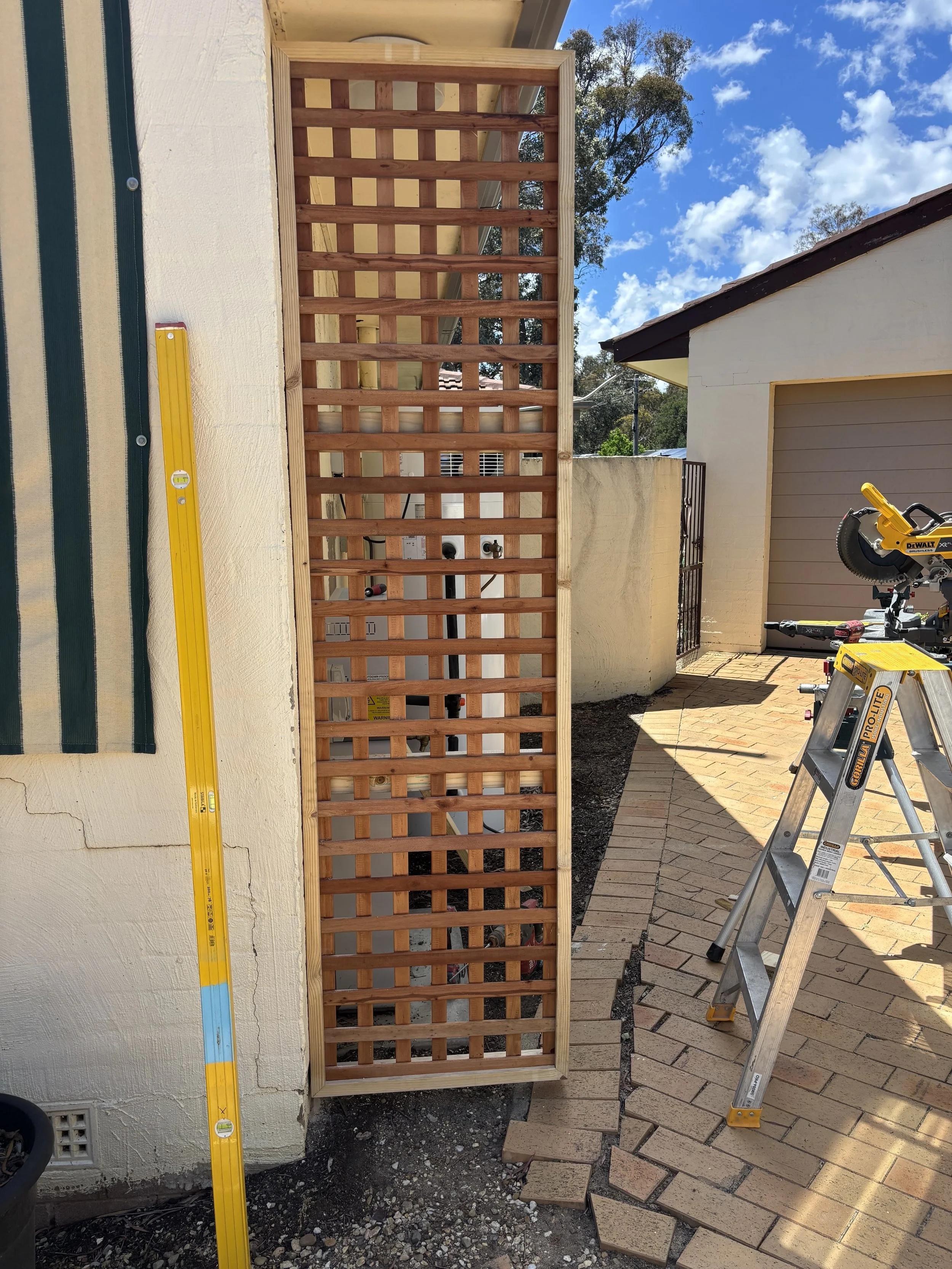 A custom lattice privacy screen built and installed to provide a more appealing finish to a backyard area.