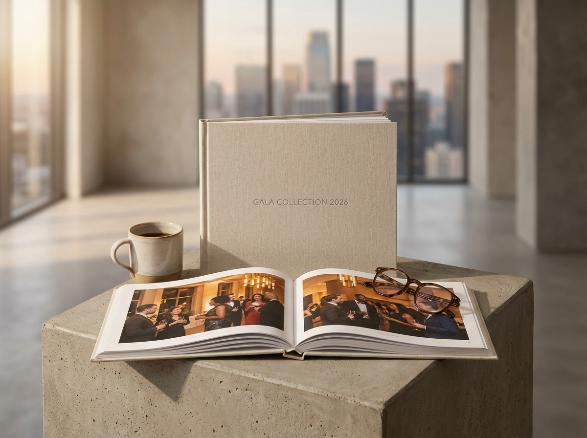An open photo album on a concrete surface showing images of people at a formal event, a pair of glasses, a cup of coffee, and a closed album titled "GALA COLLECTION 2026" with a city skyline in the background.