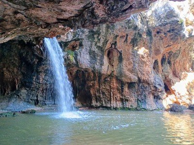 A small waterfall flowing into a pool of water surrounded by rocky cliffs.