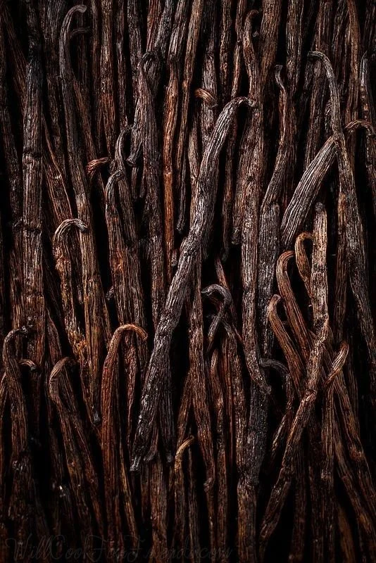 Close-up of dark brown vanilla beans, showing their wrinkled texture and elongated shape.