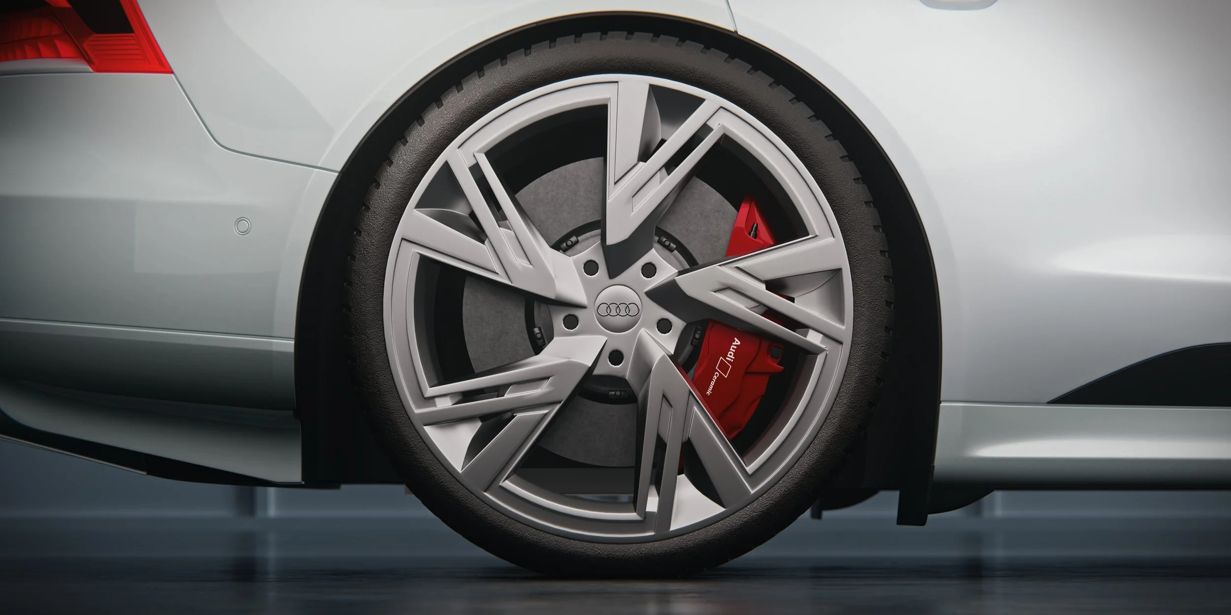 Detailaufnahme einer silbernen Audi-e-tron-GT-Leichtmetallfelge mit sichtbarer Bremsscheibe und rotem Bremssattel. Close-up of a silver Audi e-tron GT alloy wheel with a visible brake disc and red brake caliper.