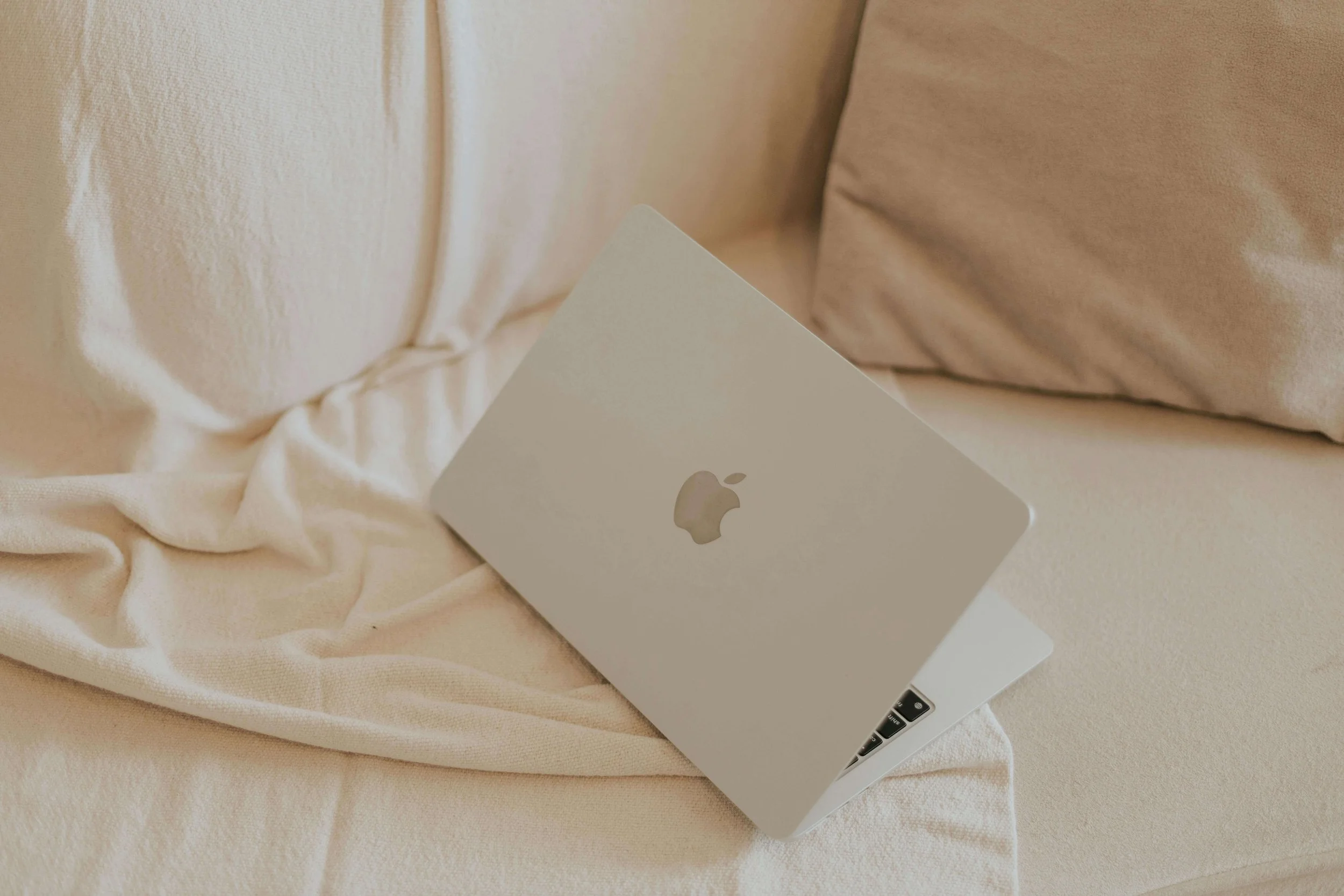 A silver Apple MacBook of a masshealth accepting doula lying on a cream-colored cloth