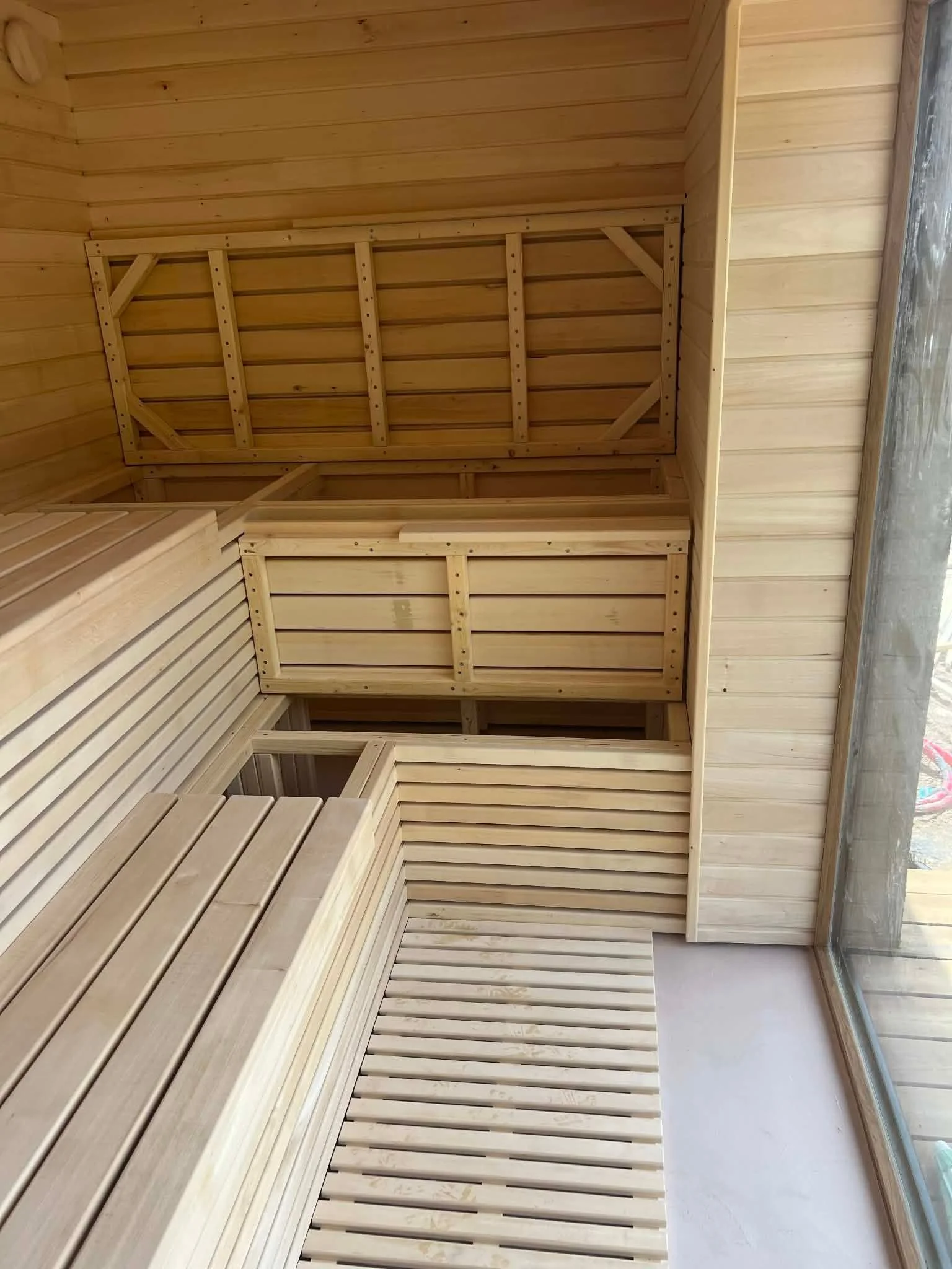 Interior of a Nordbadstu timber sauna with light two-tier benches