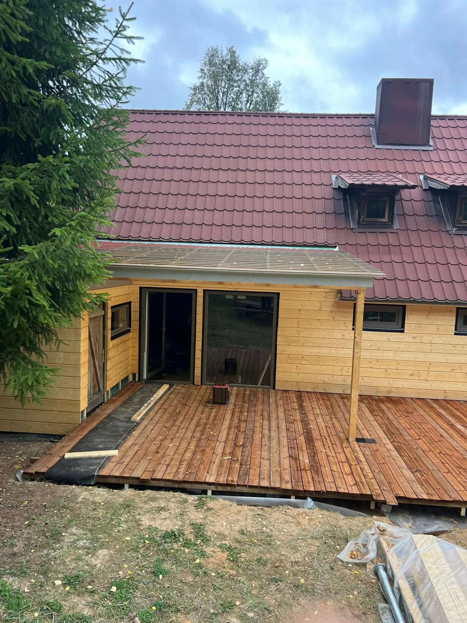 Nordbadstu timber sauna house with a red roof and a wooden terrace
