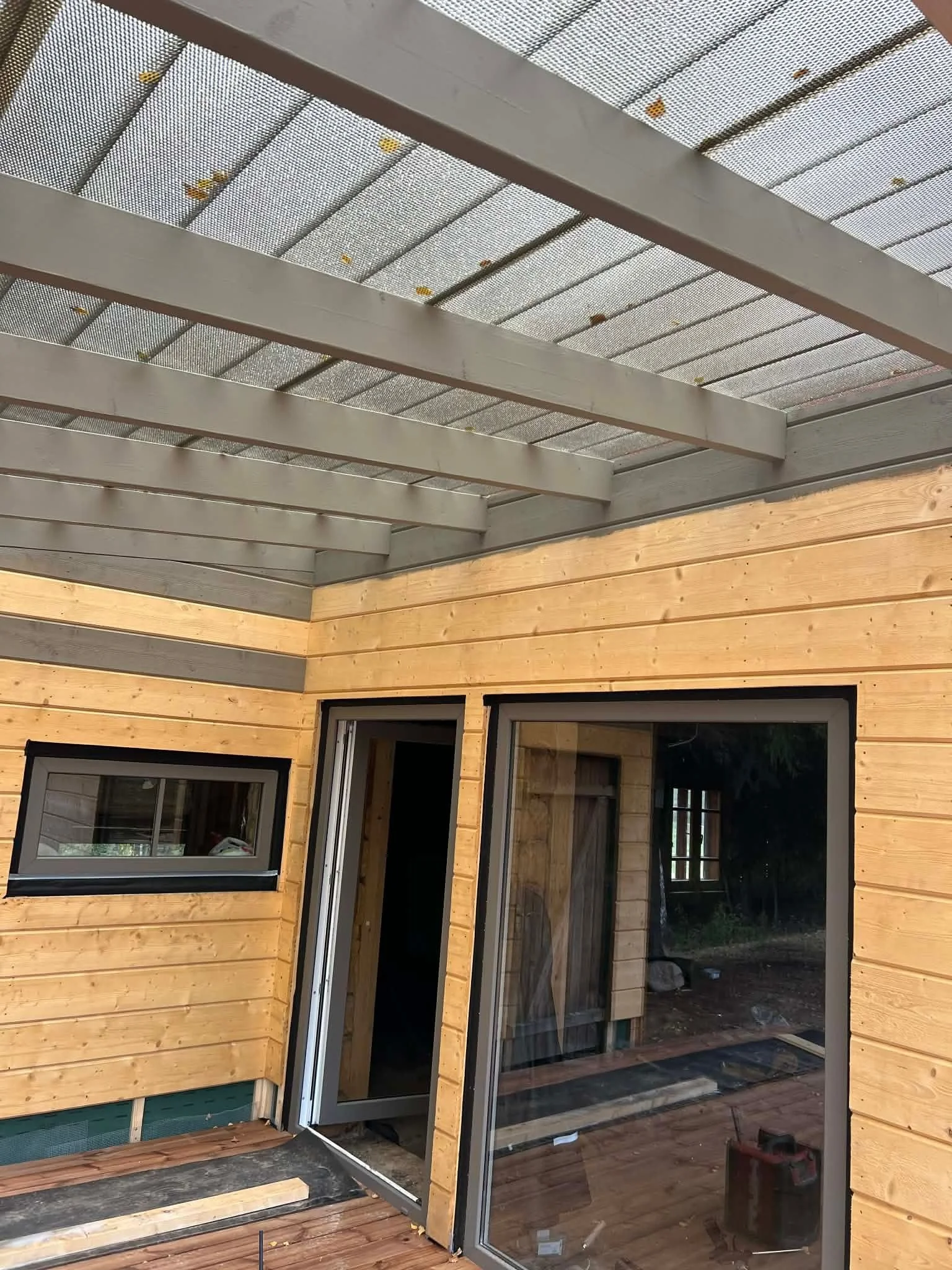 Nordbadstu timber sauna exterior with glass doors and a covered terrace