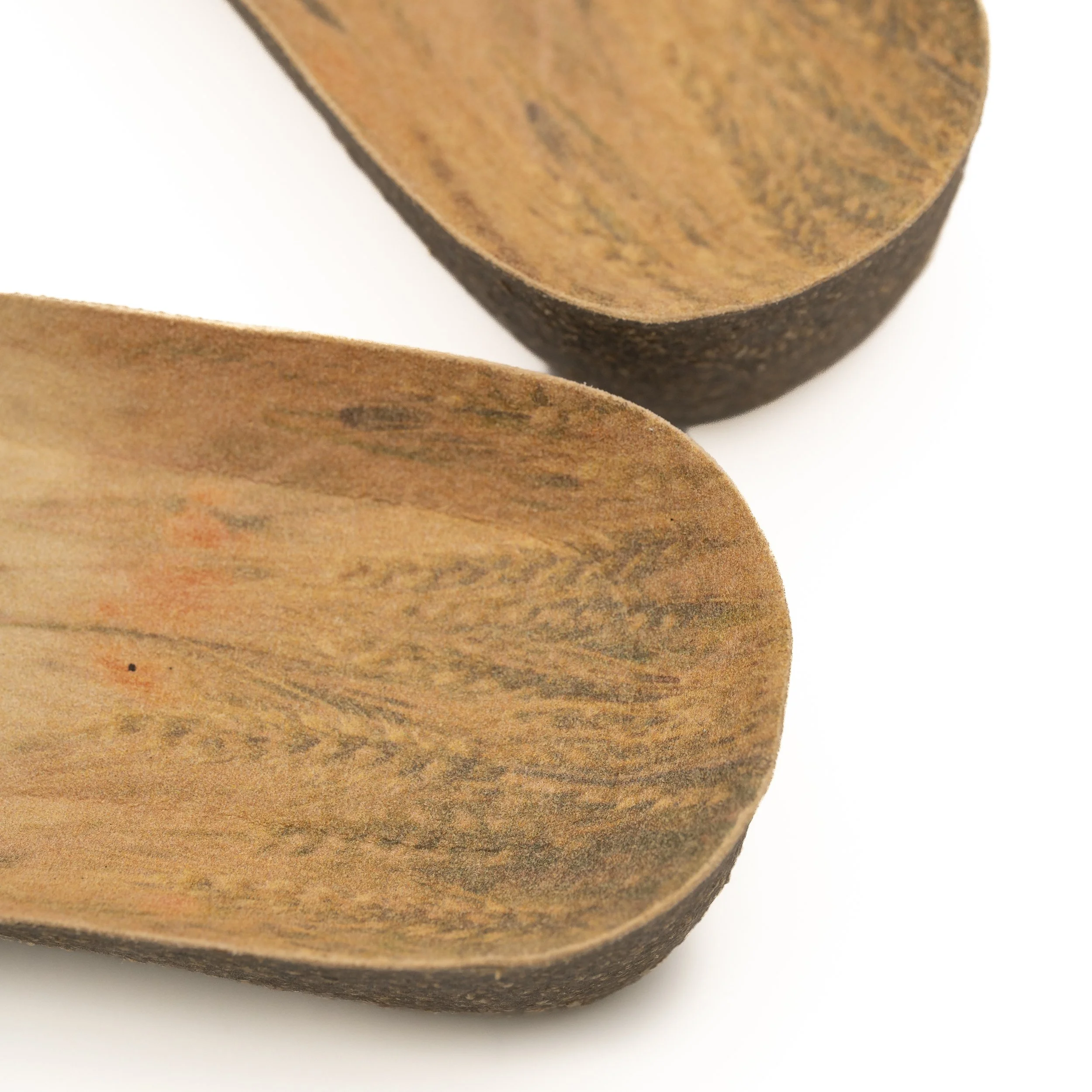 Primer plano de la punta de una cuchara de madera, mostrando la textura de la madera y su color marrón claro con vetas oscuras.