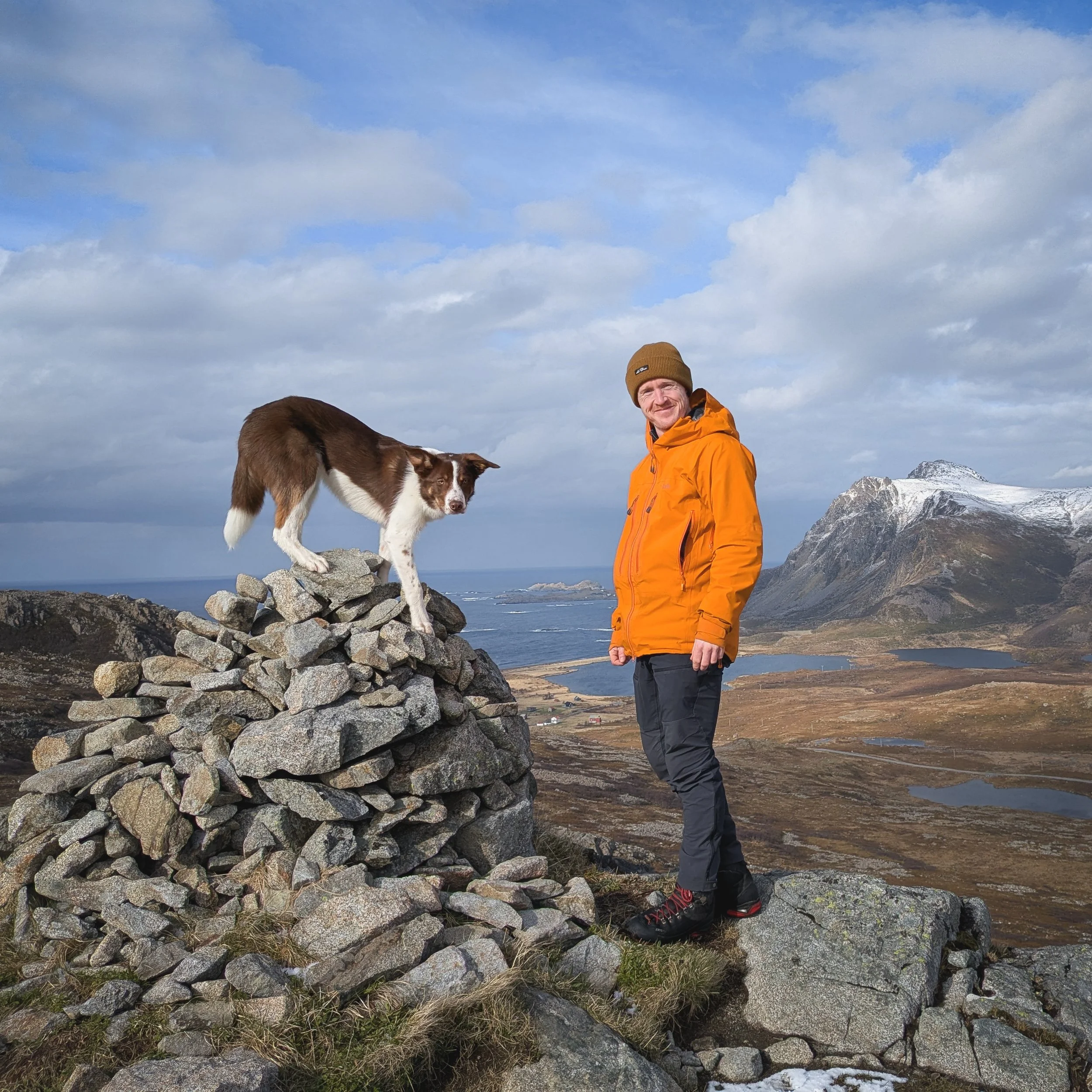 Sam and his dog standing on a mountain summit near Nykvåg