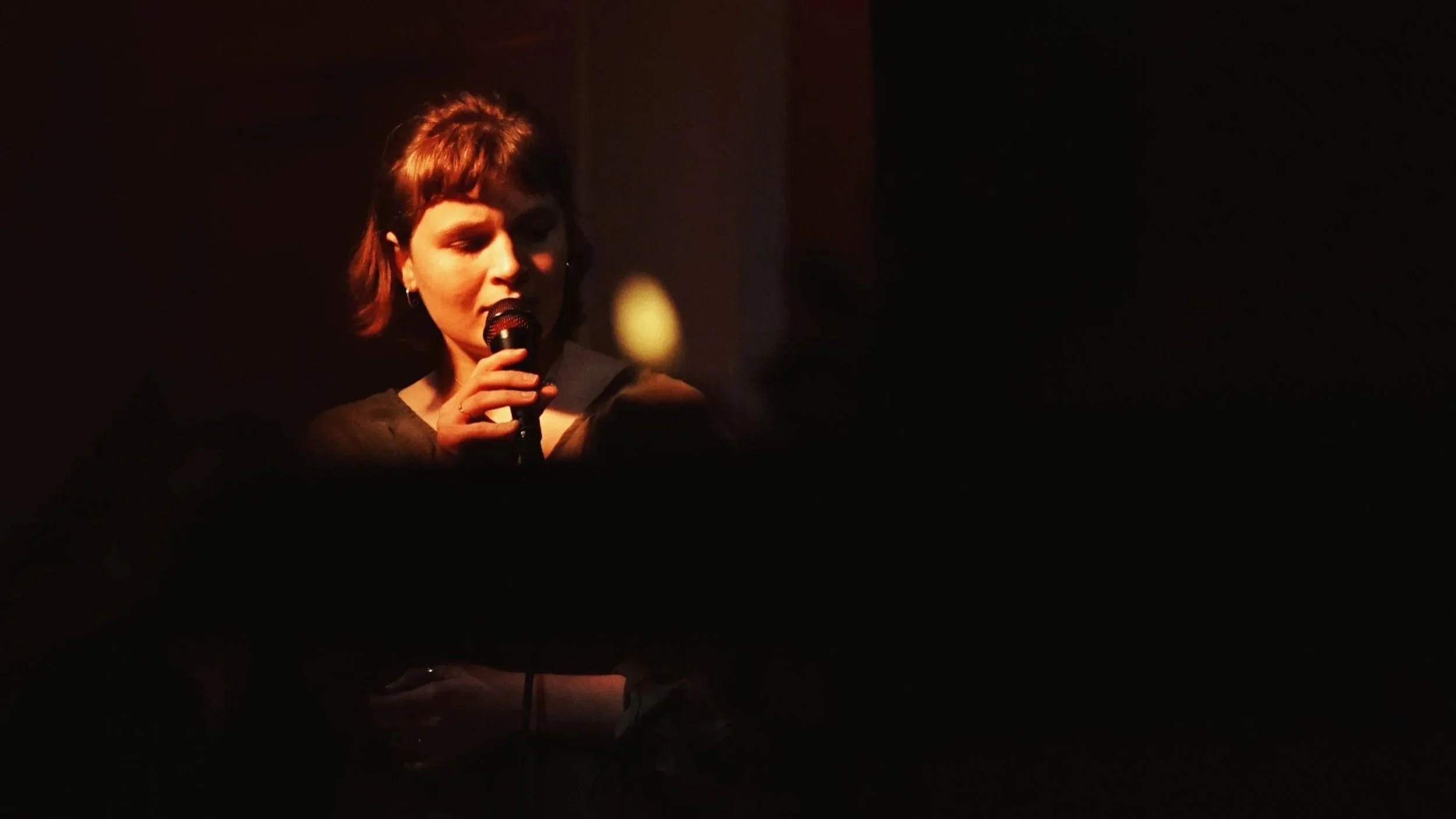En kvinde med kort hår synger i mikrofon til jazzkoncert i Villa Lucerna.