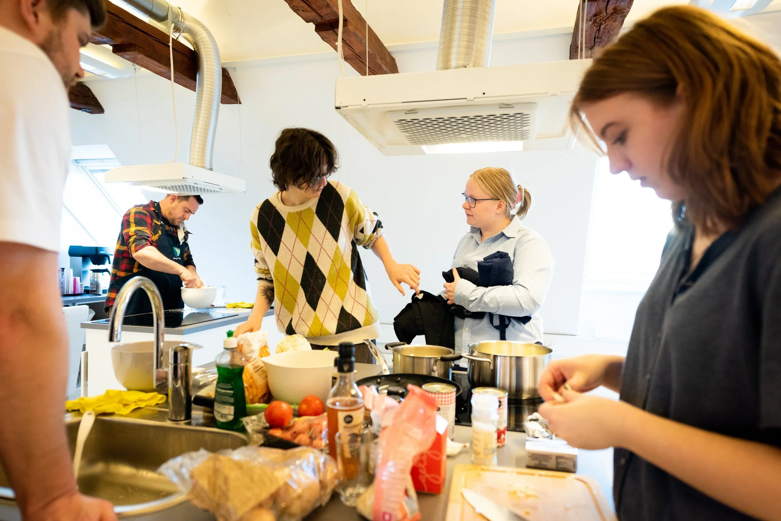 En gruppe mennesker laver mad i et køkken.