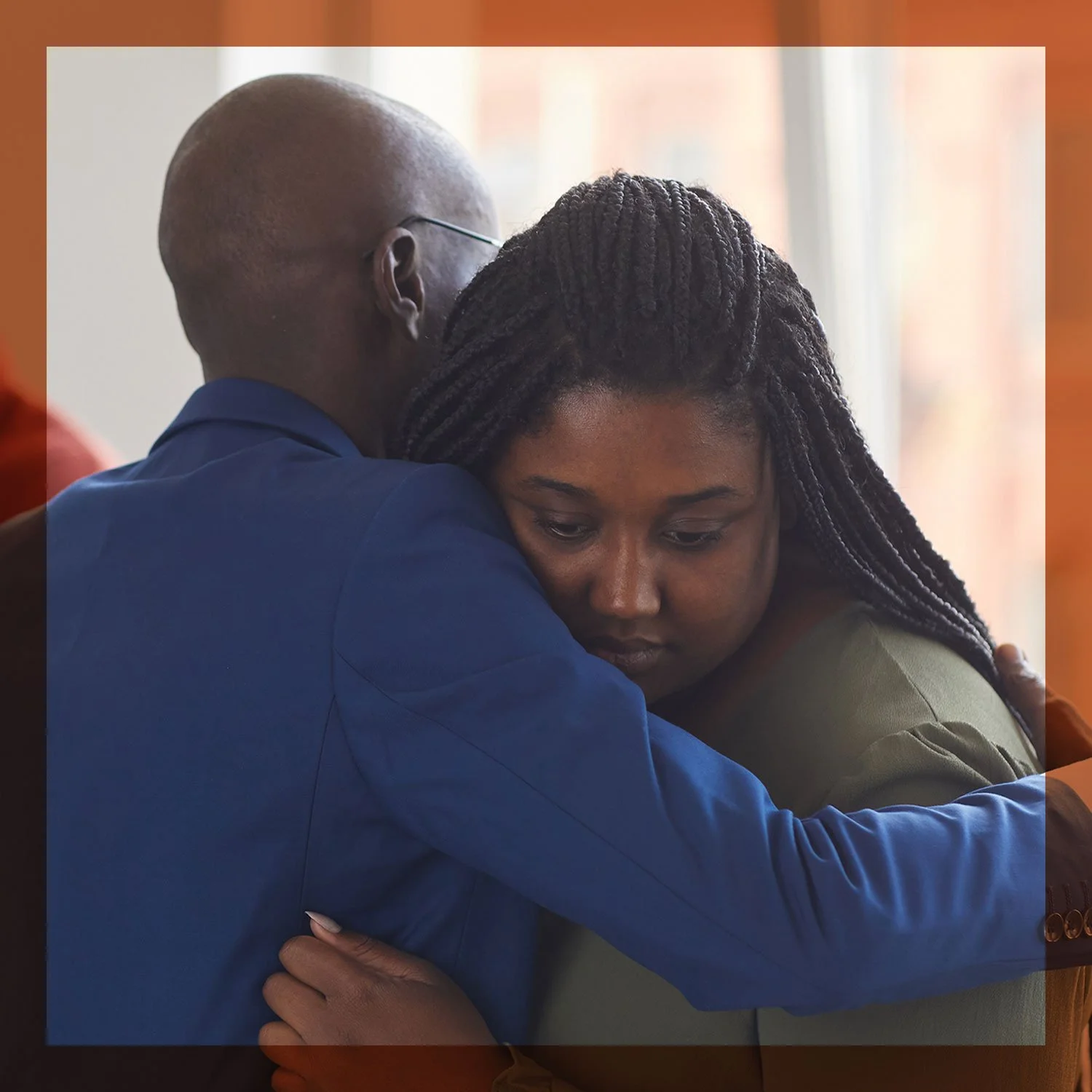 A man and a woman hugging each other tightly, showing emotion and comfort, with the woman resting her head on the man's shoulder.