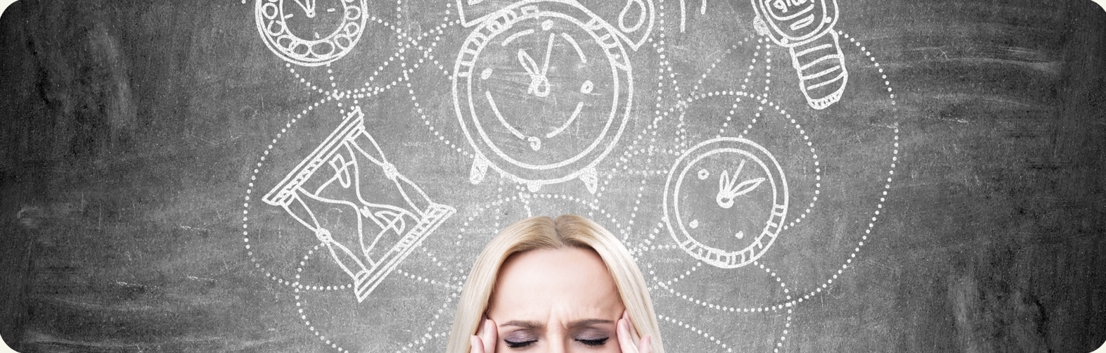 A woman holds her head in frustration in front of a chalkboard with doodles of clocks, an hourglass, an alarm clock, and light bulbs drawn on it.