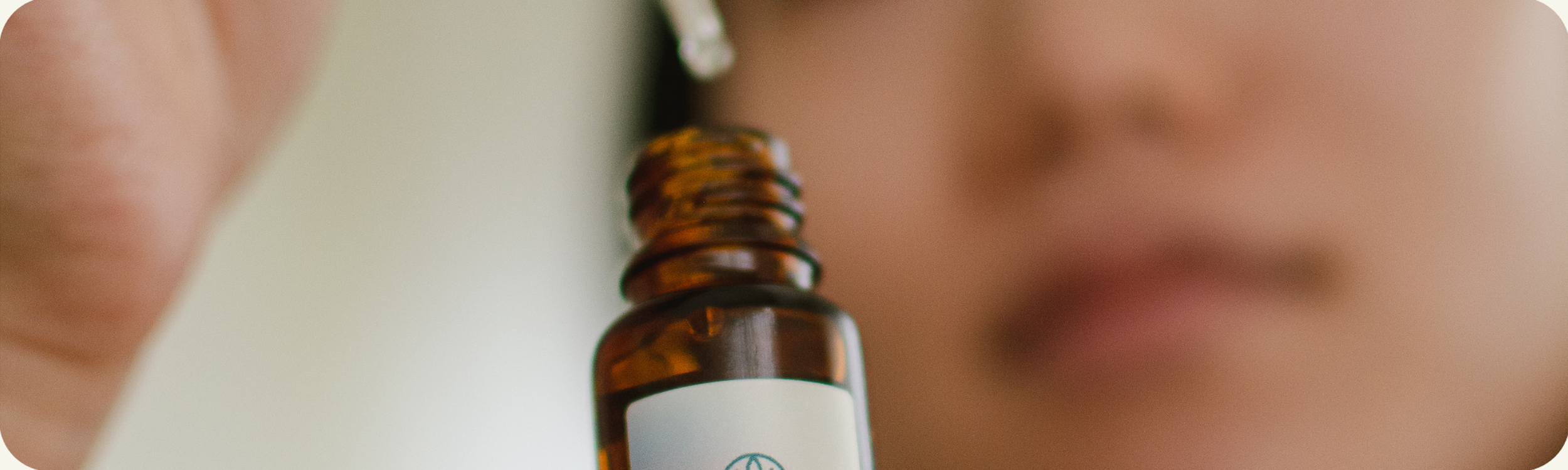 Close-up of a small amber glass bottle with a white label and a person in the background.