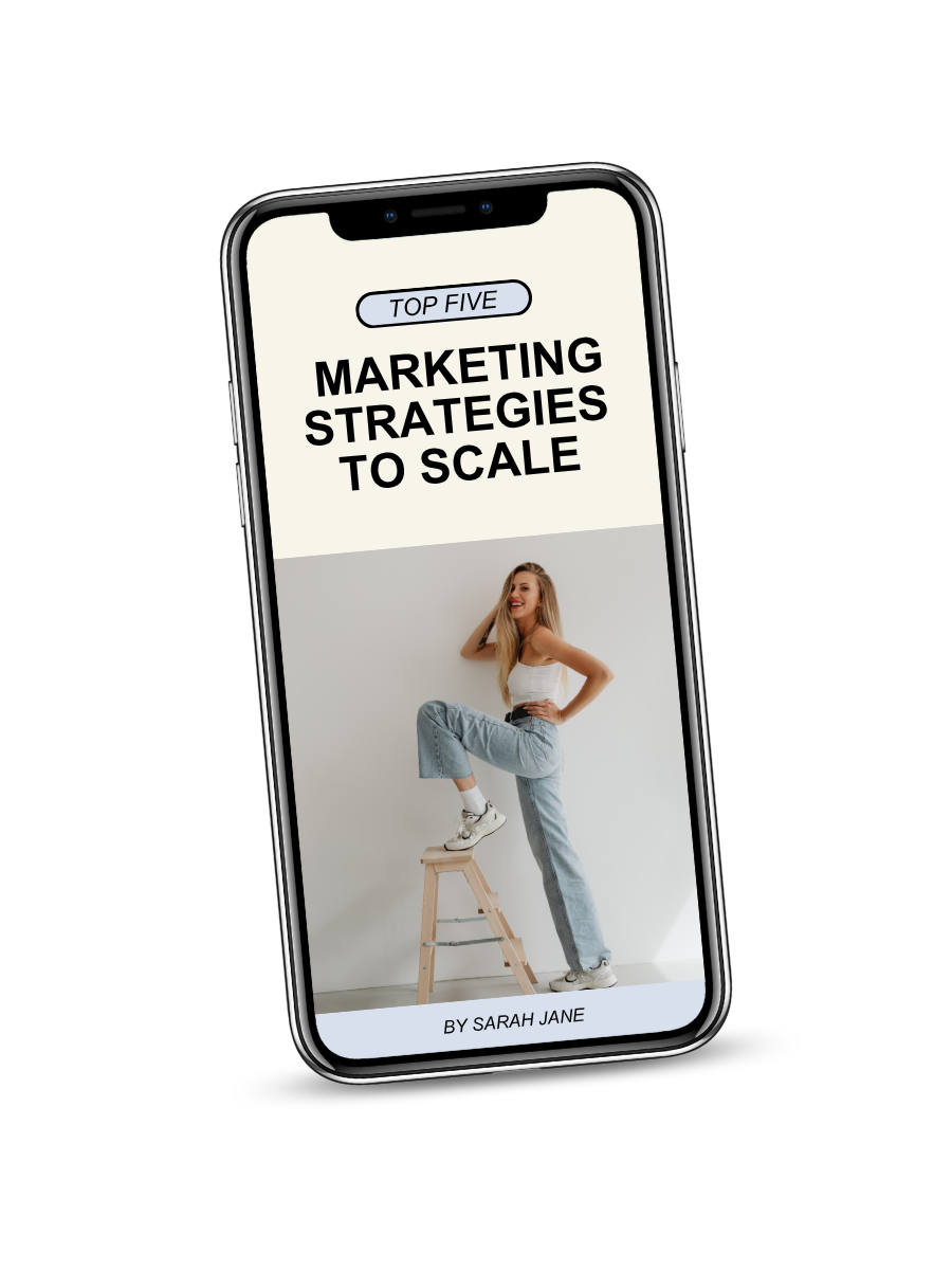 Smartphone displaying a book cover titled 'Top Five Marketing Strategies to Scale' by Sarah Jane, featuring a woman in casual clothing posing with one foot on a stool.