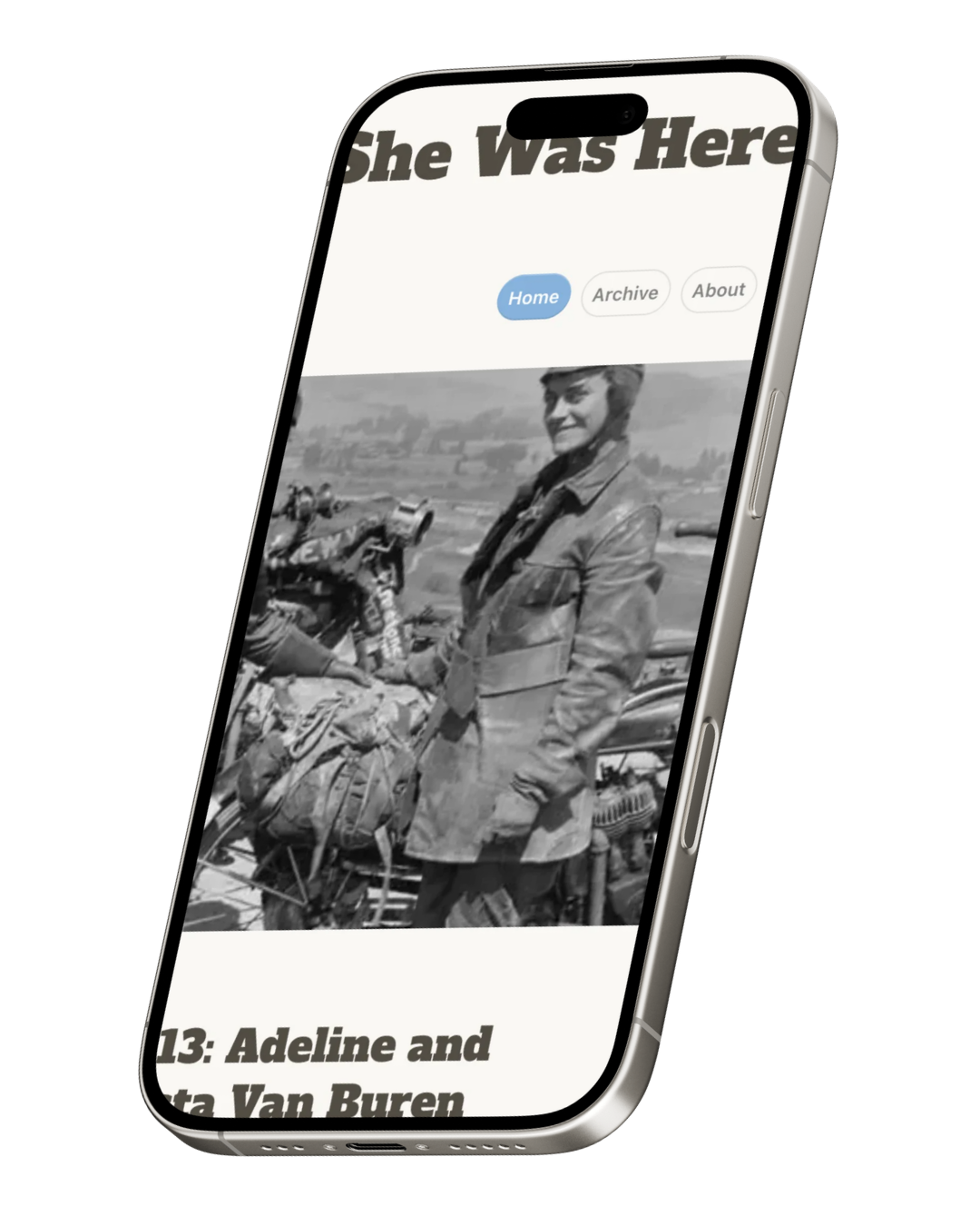 A smartphone displaying a webpage titled "She Was Here" with navigation options and a black-and-white photograph of a woman with a motorcycle, wearing a jacket, in an outdoor setting.