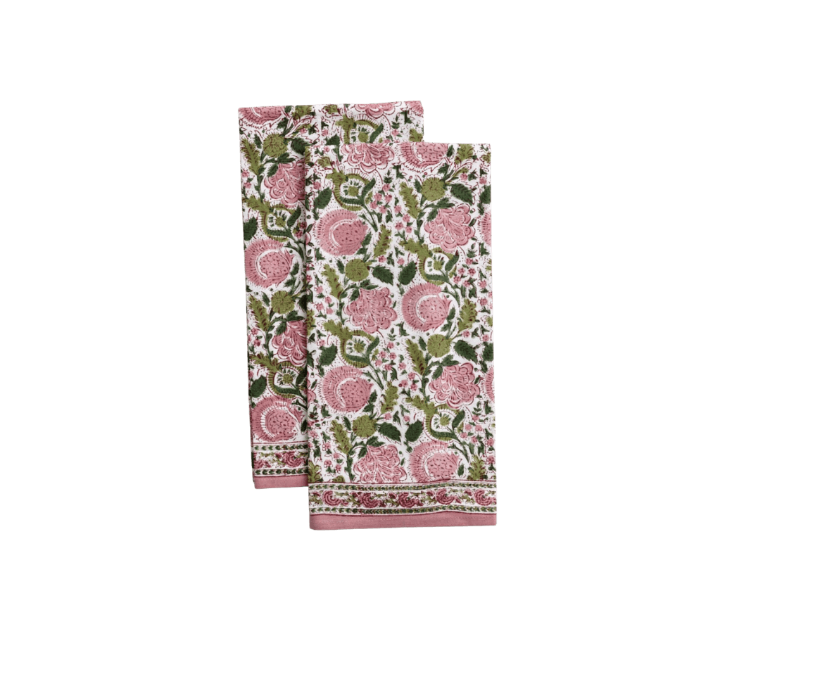 Two folded floral-printed towels with pink, green, and white pattern, one on top of the other, against a black background.