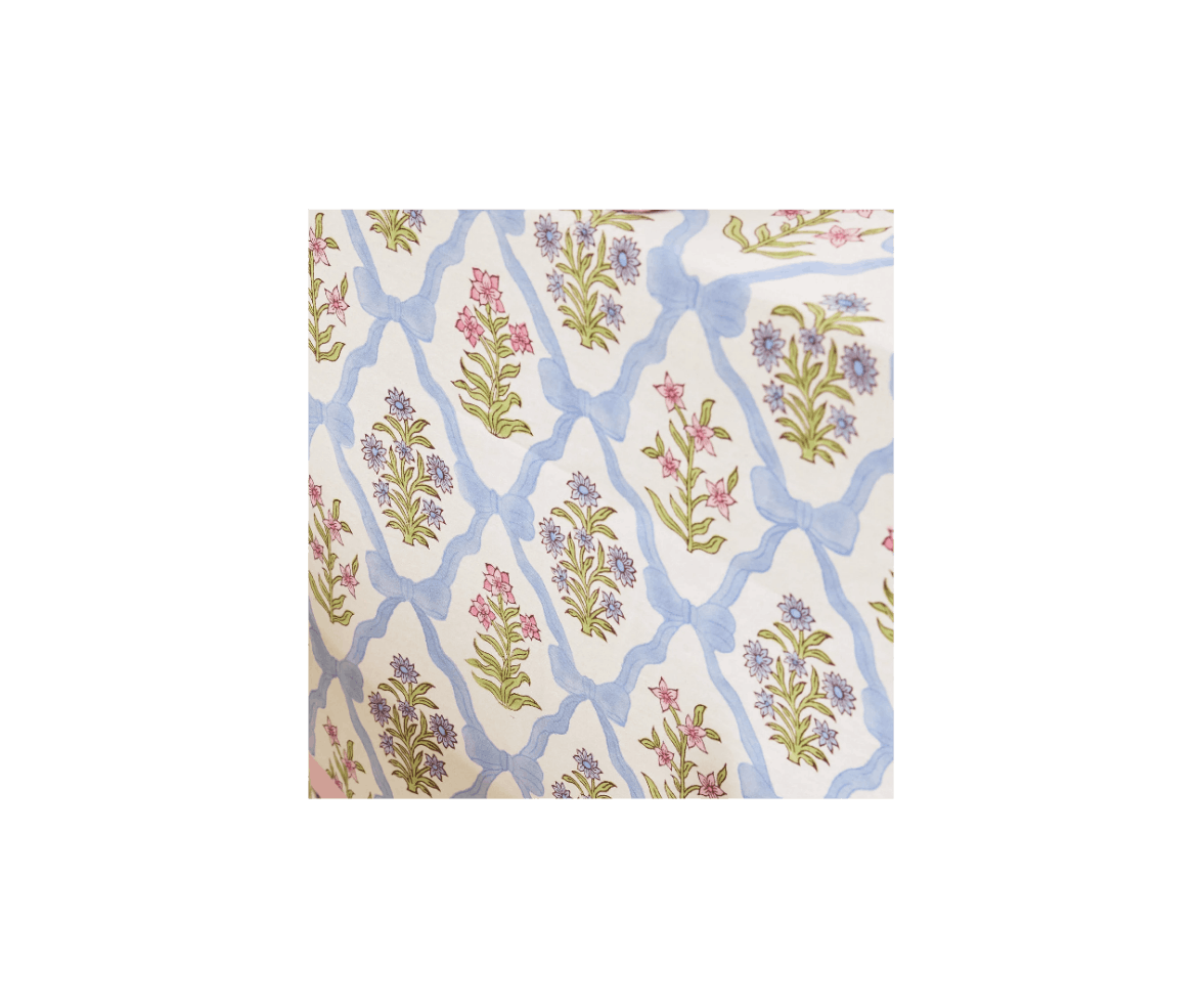 Pattern featuring pink and blue flowers with green leaves, connected by blue ribbons, on a white background.