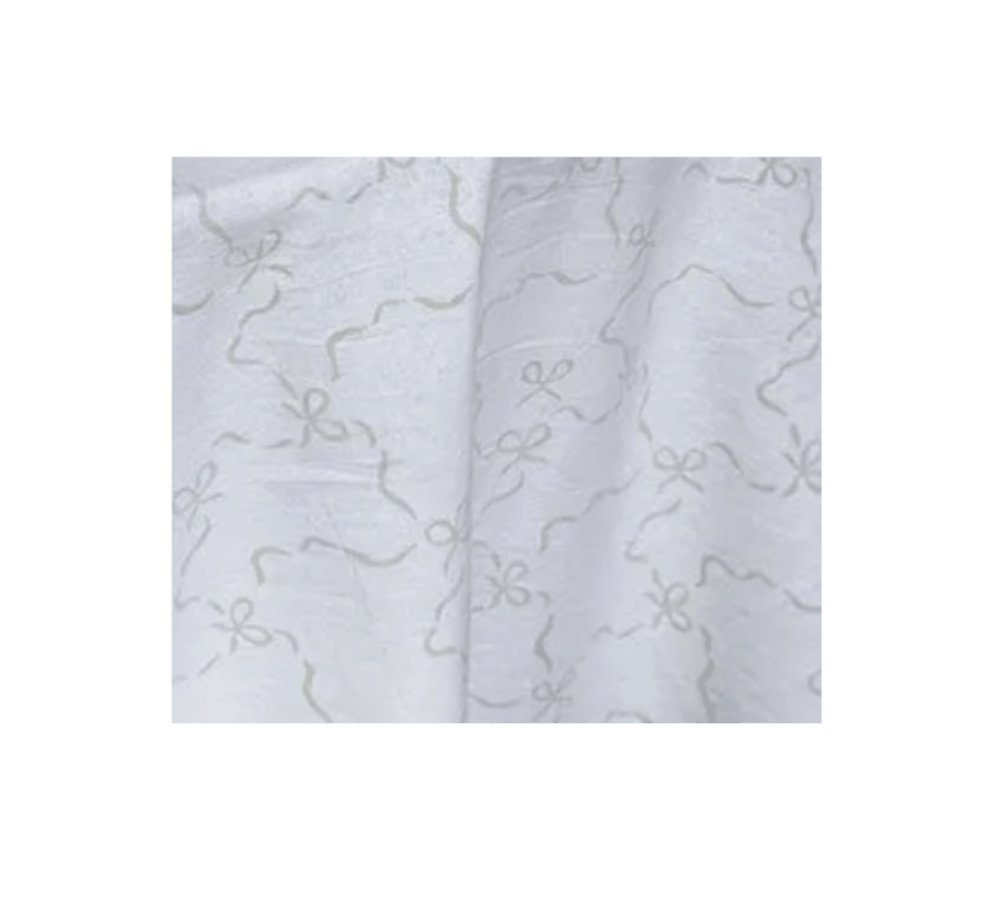 Close-up of a white fabric with a subtle pattern of ribbon bows and twisting lines.