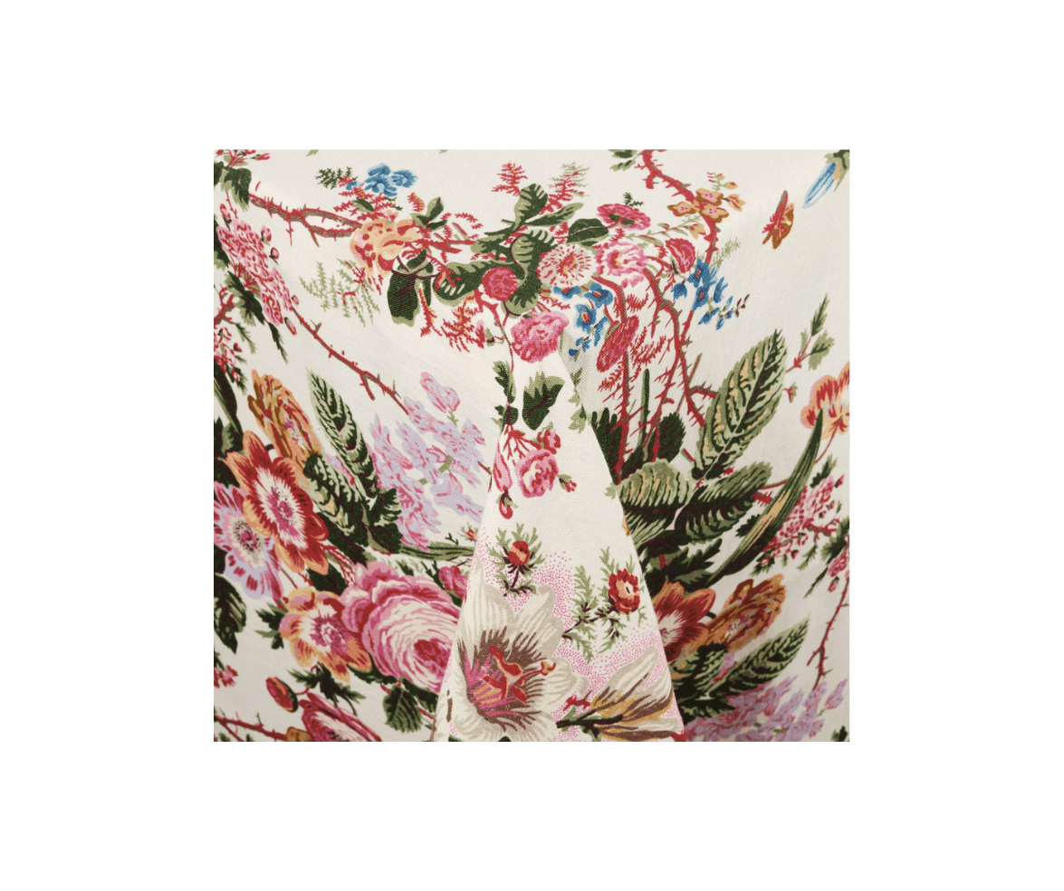 A close-up of a floral-patterned fabric with pink, red, green, and blue flowers and leaves on a white background.