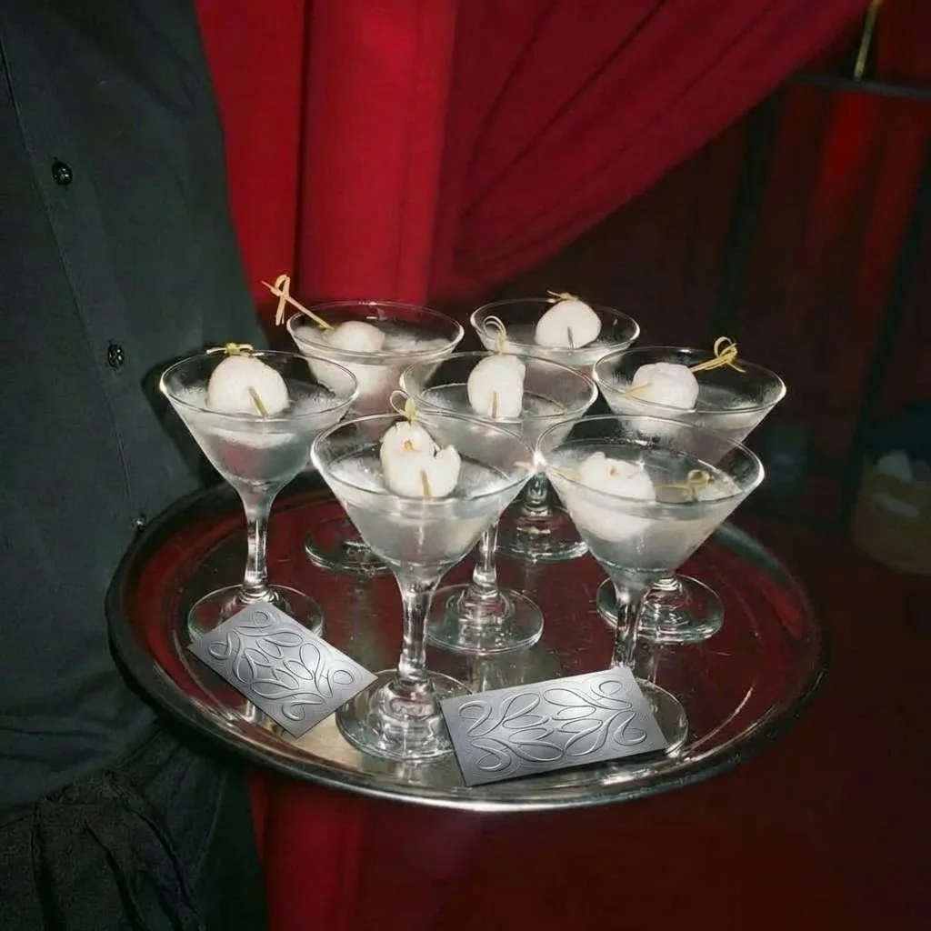 Seven martini glasses with white garnishes, possibly lychees or pearls, on a silver tray.
AS THE EXPERIENCE BRANDING. Events in Barcelona. organization of events. Modern and creative agency