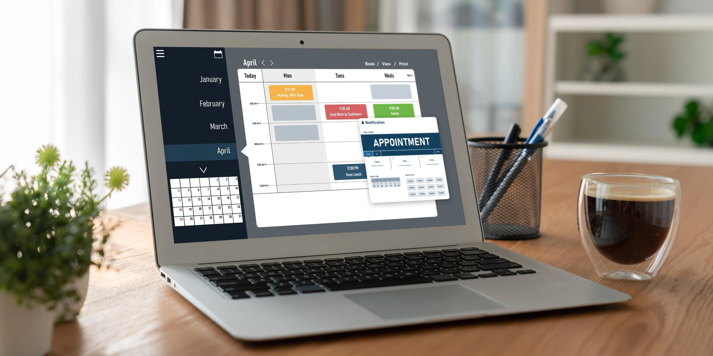 Laptop displaying a digital calendar and appointment scheduling app. A cup of coffee, a plant, and a pen holder are on a wooden table in a bright room.