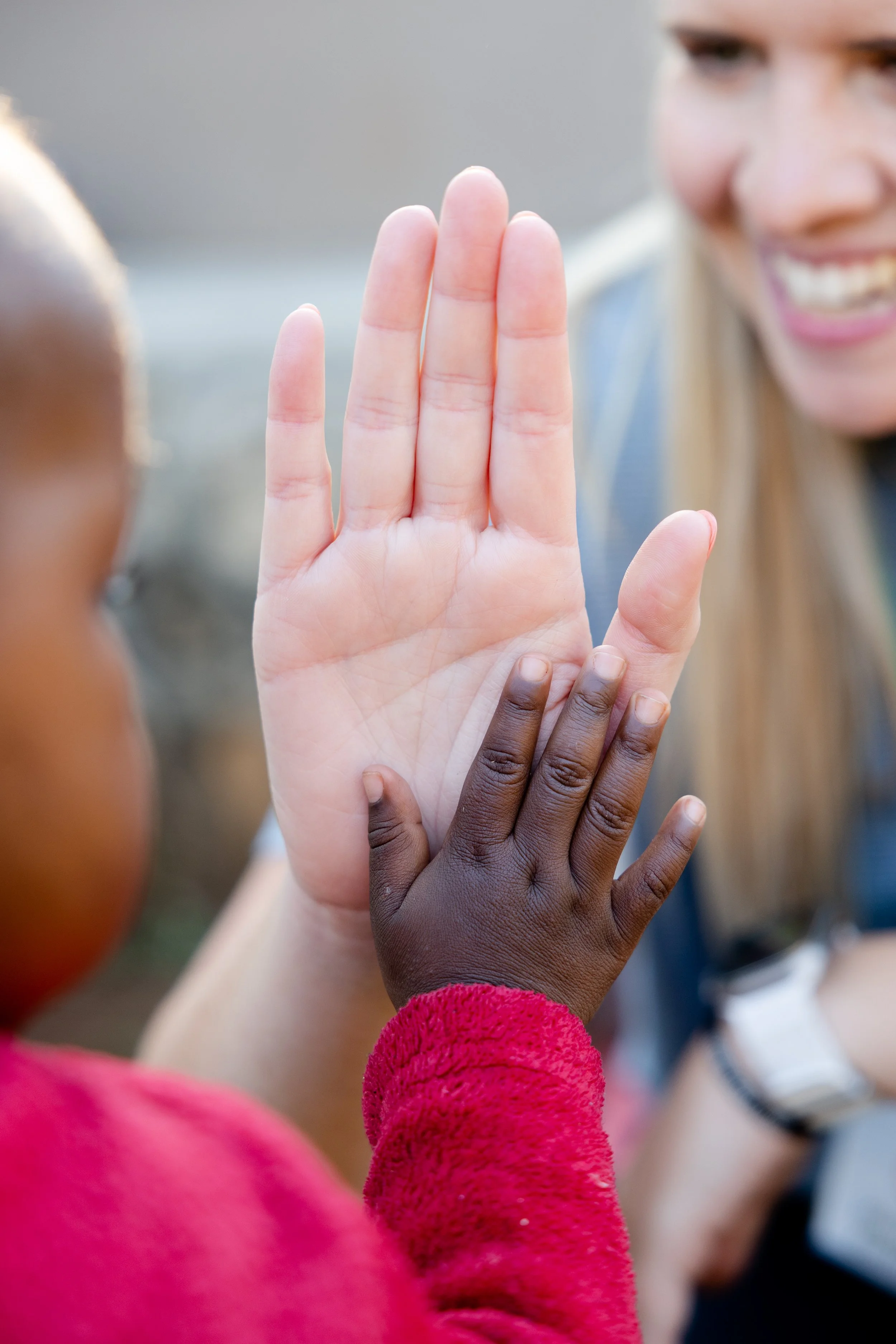 Close-up of a group of people with different skin tones raising their hands together for a high five.
