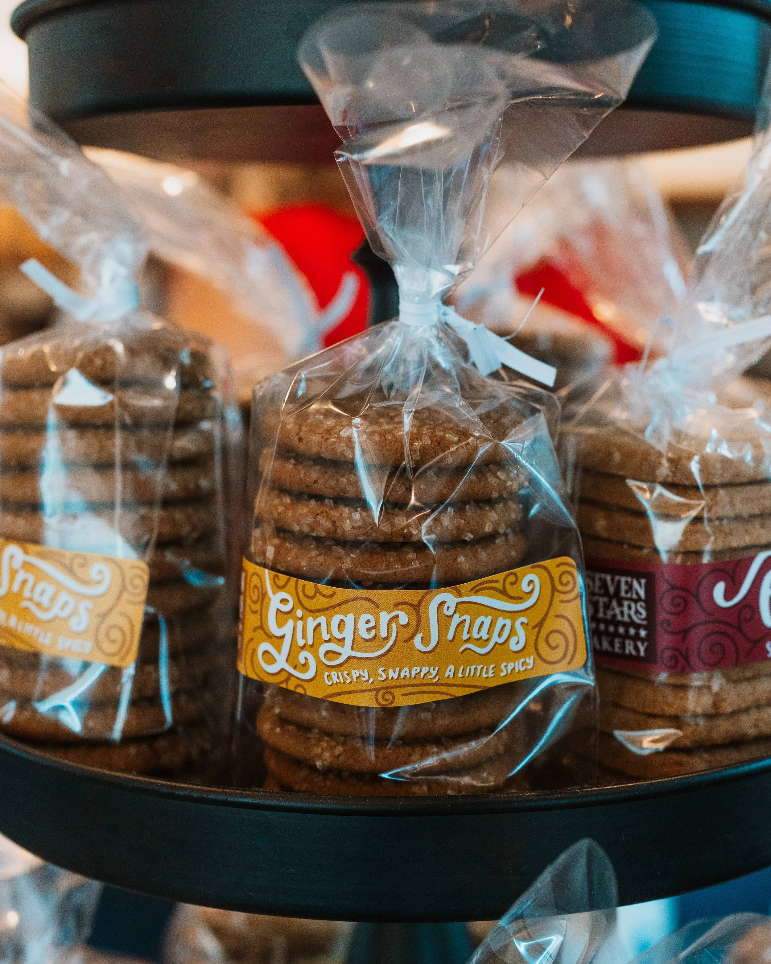 Close-up of packaged ginger snaps cookies on a black surface, with colorful blurred background