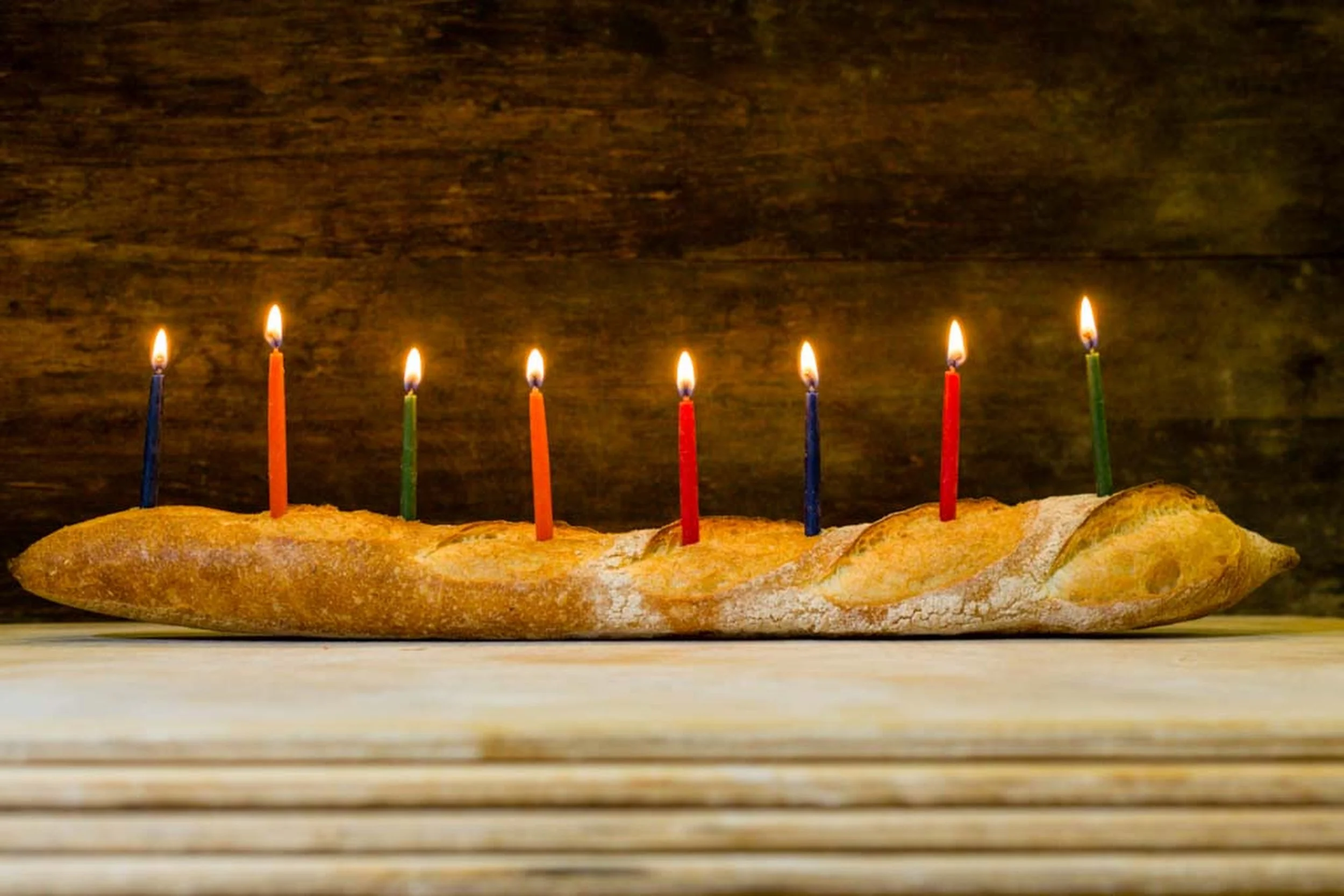Rustic Seven Stars Bakery loaf topped with six lit candles for a celebration.