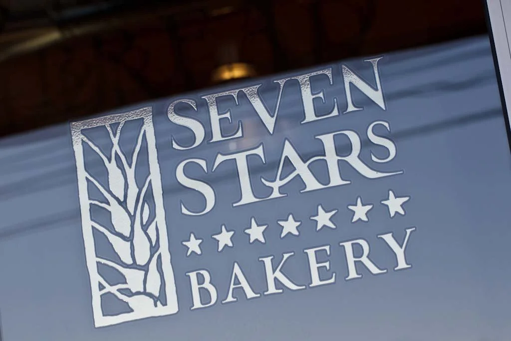 Sign for Seven Stars Bakery with a wheat symbol and star graphics.