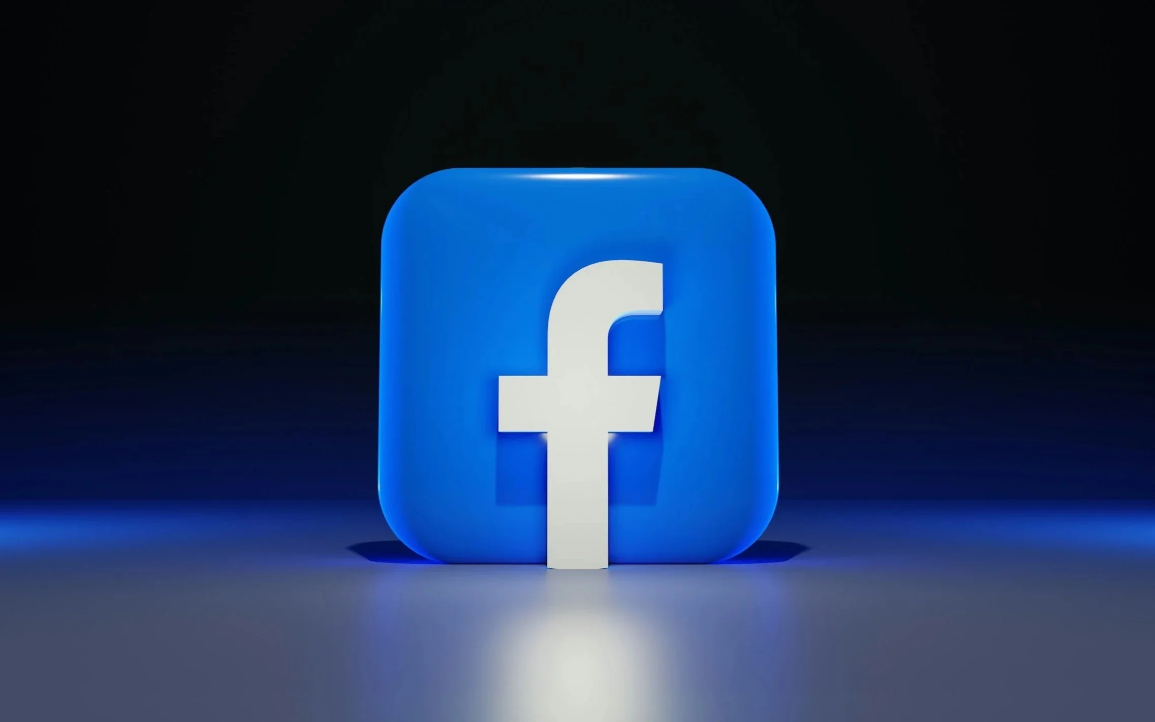 Facebook logo illuminated in blue against a dark background.