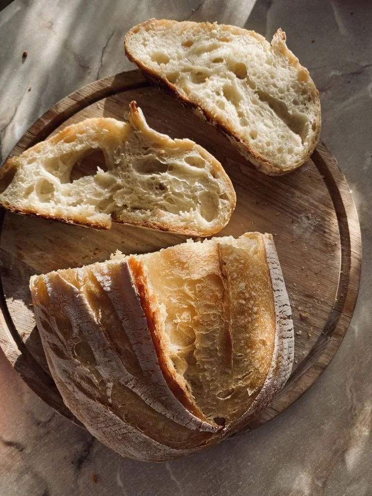 Sliced loaf of rustic bread on a wooden cutting board.