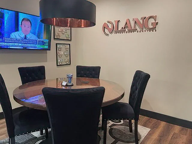 A round wooden table with four black upholstered chairs in a meeting room. Lang Investment Services is a financial advisor based in Monument, CO.