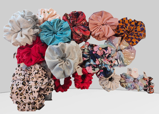 Collection of colorful scrunchies and hair accessories arranged on a white surface.