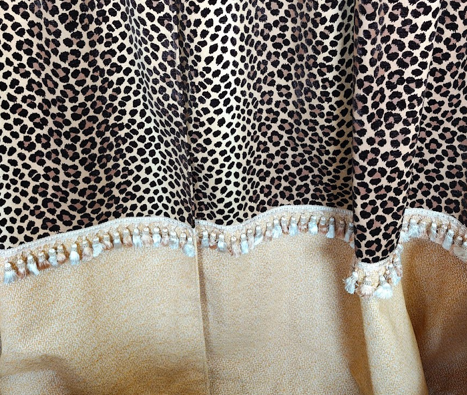 Close-up of a fabric with a leopard print pattern, decorated with pearl beads at the border.