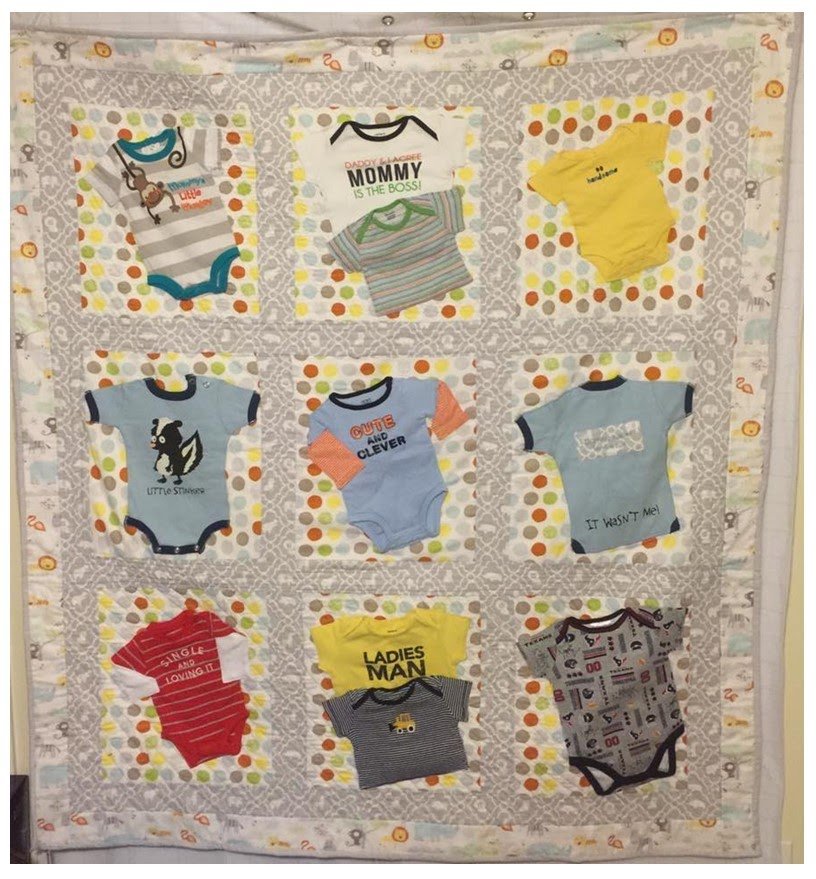 A quilt with nine pockets, each holding children's clothing or accessories, including baby onesies, shirts, and a hat, with colorful polka dot and patterned fabric surrounding each pocket.