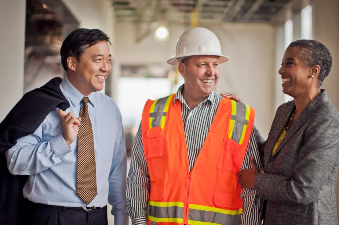 A businessperson and a construction professional in friendly conversation on site.