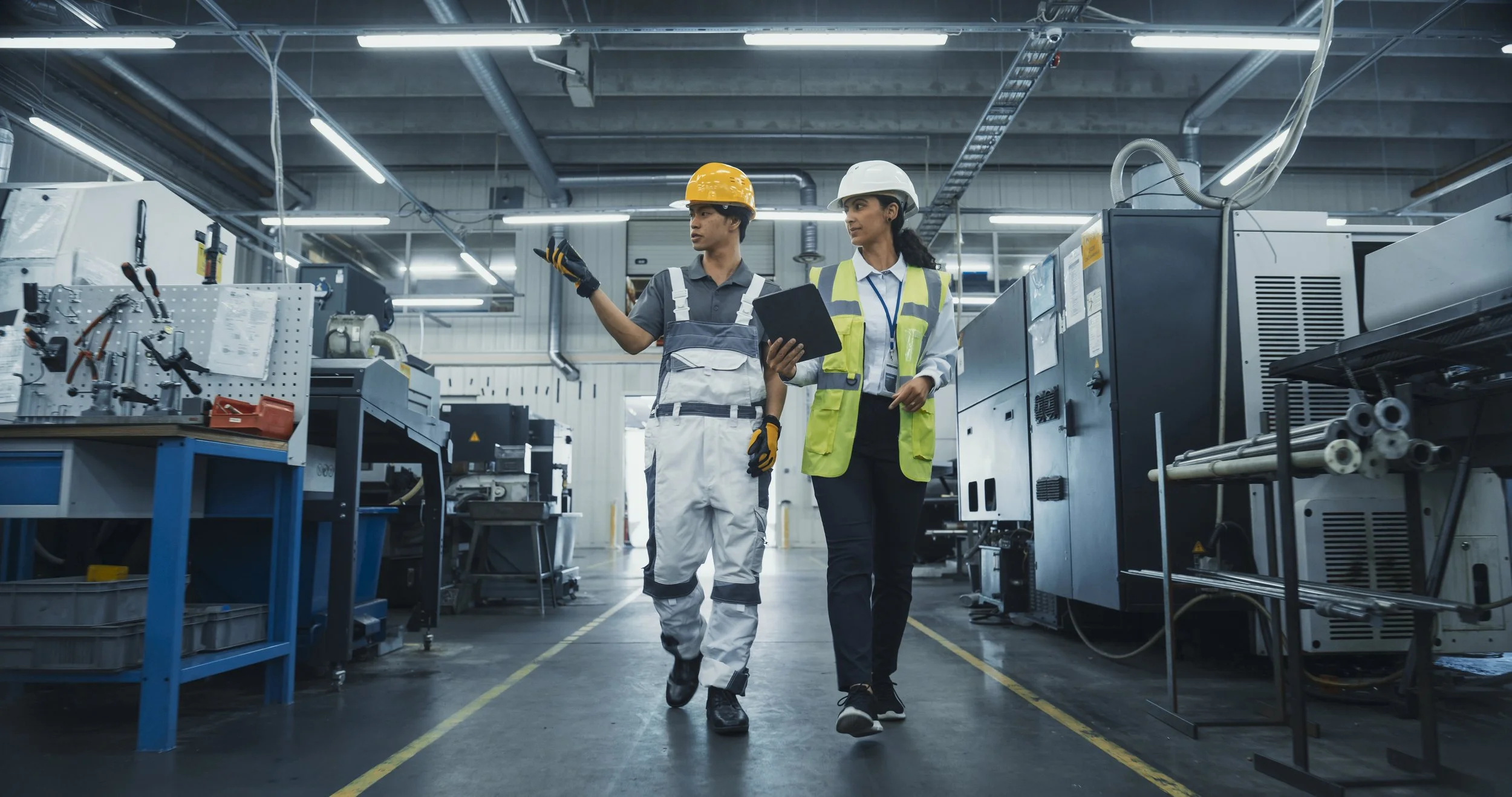An advisor and an operations team member in discussion while walking through a working production facility.