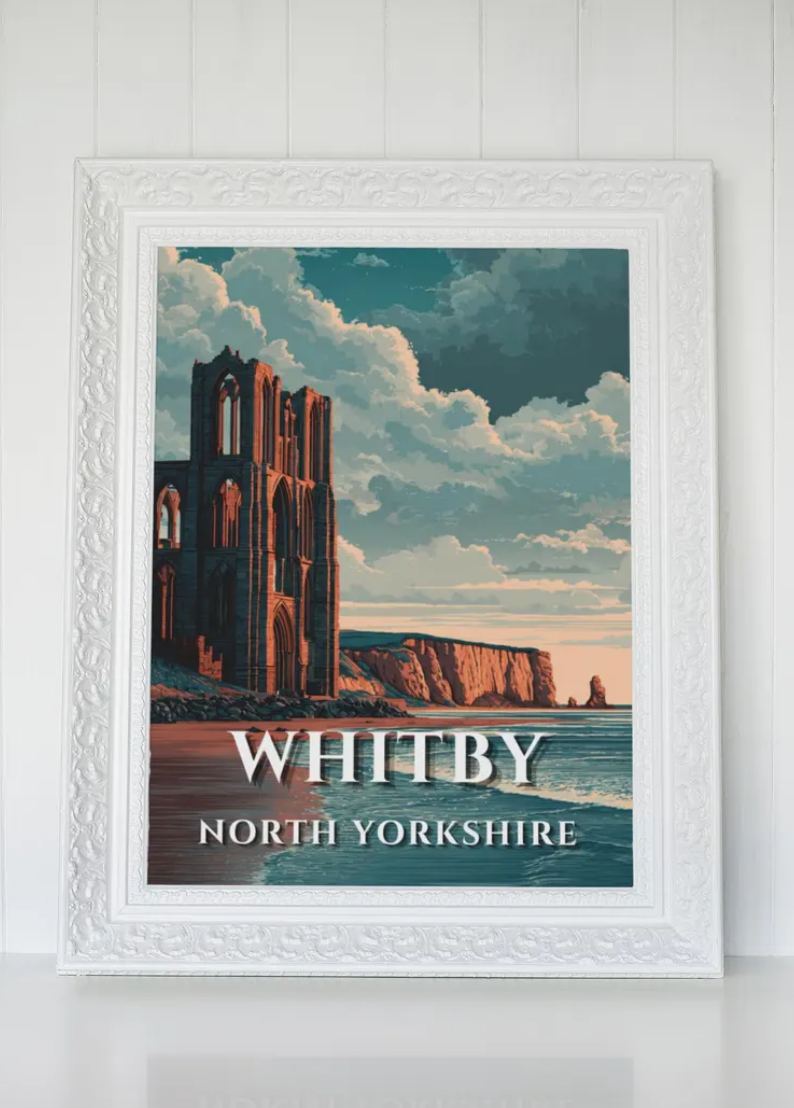 A framed poster of Whitby, North Yorkshire, featuring a scenic view of a coastline with a historic, ruined gothic-style building and dramatic clouds in the sky.