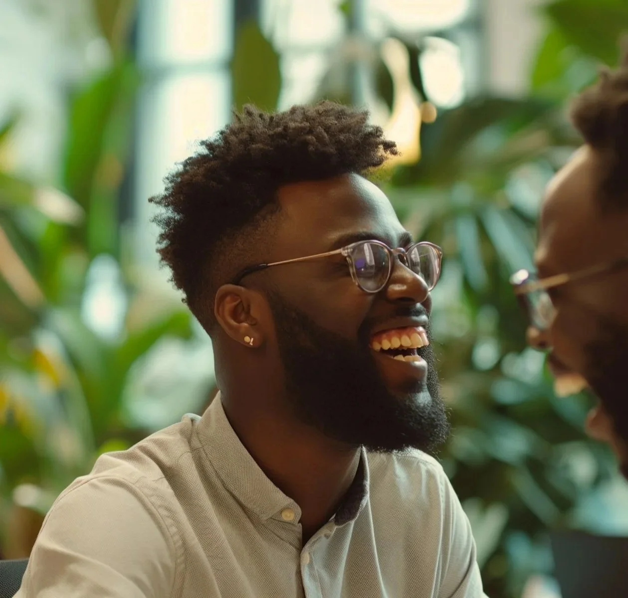 Two men, smiling and laughing, having a conversation in a green indoor setting.