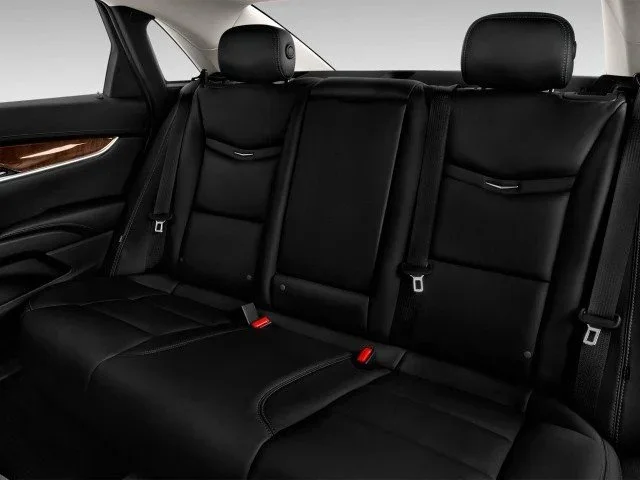 Rear car seats in black leather with headrests and seat belts.