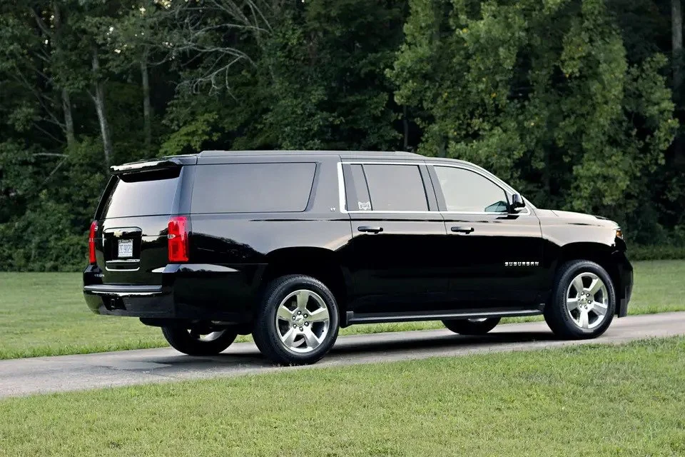 Black SUV parked on a roadside with a grassy area and trees in the background.