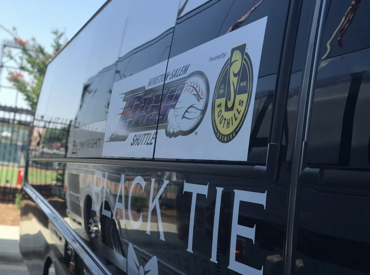 A black tie transportation shuttle with stickers promoting the Winston-Salem Dash.