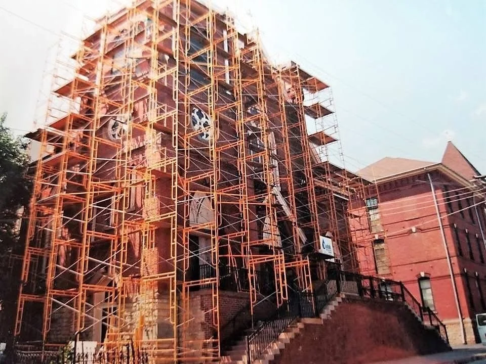 Building under construction with orange scaffolding and brick exterior.